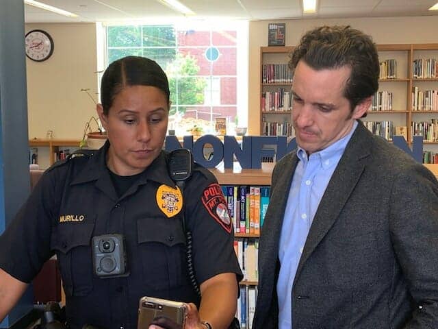 a police officer and a man are looking at a cell phone in a library .