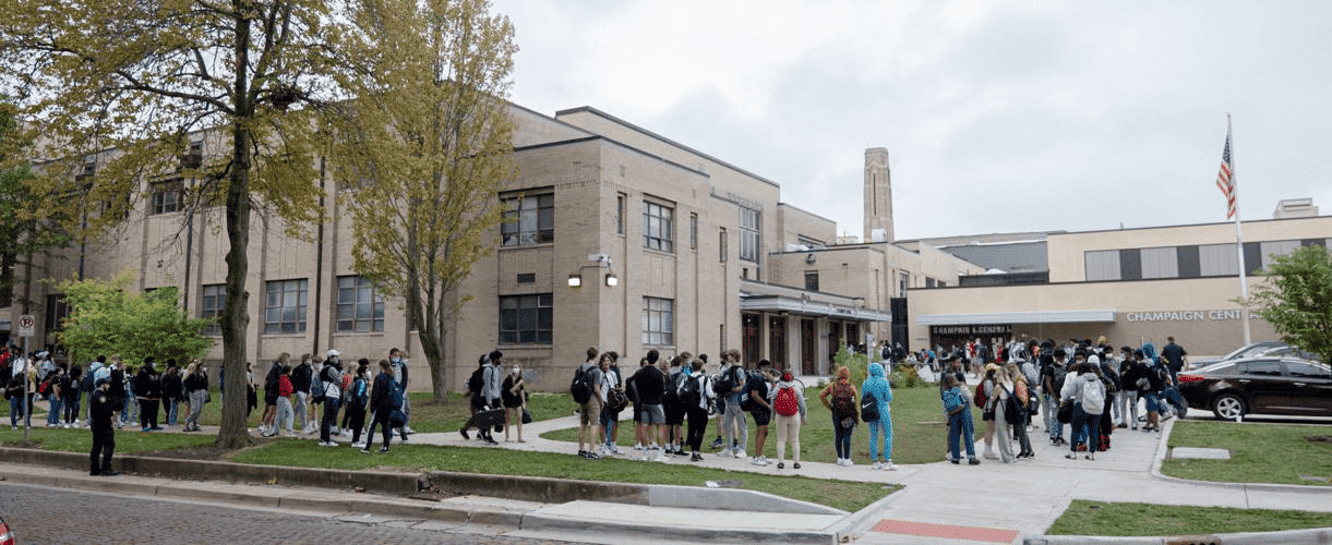a large group of people are gathered in front of a school
