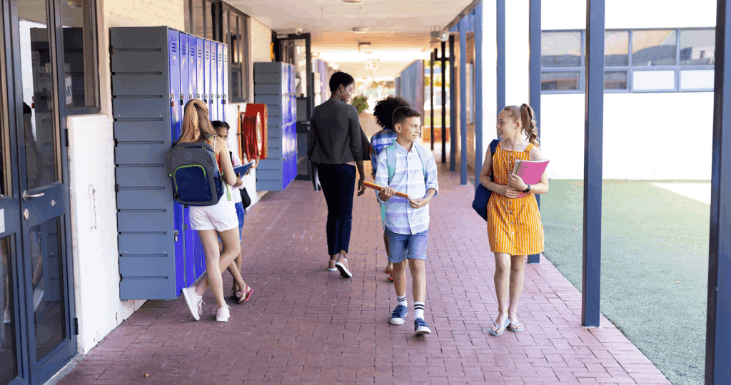 a group of children are walking down a hallway in front of lockers