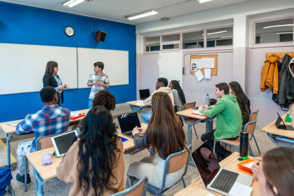 a teacher is giving a presentation to a group of students in a classroom .