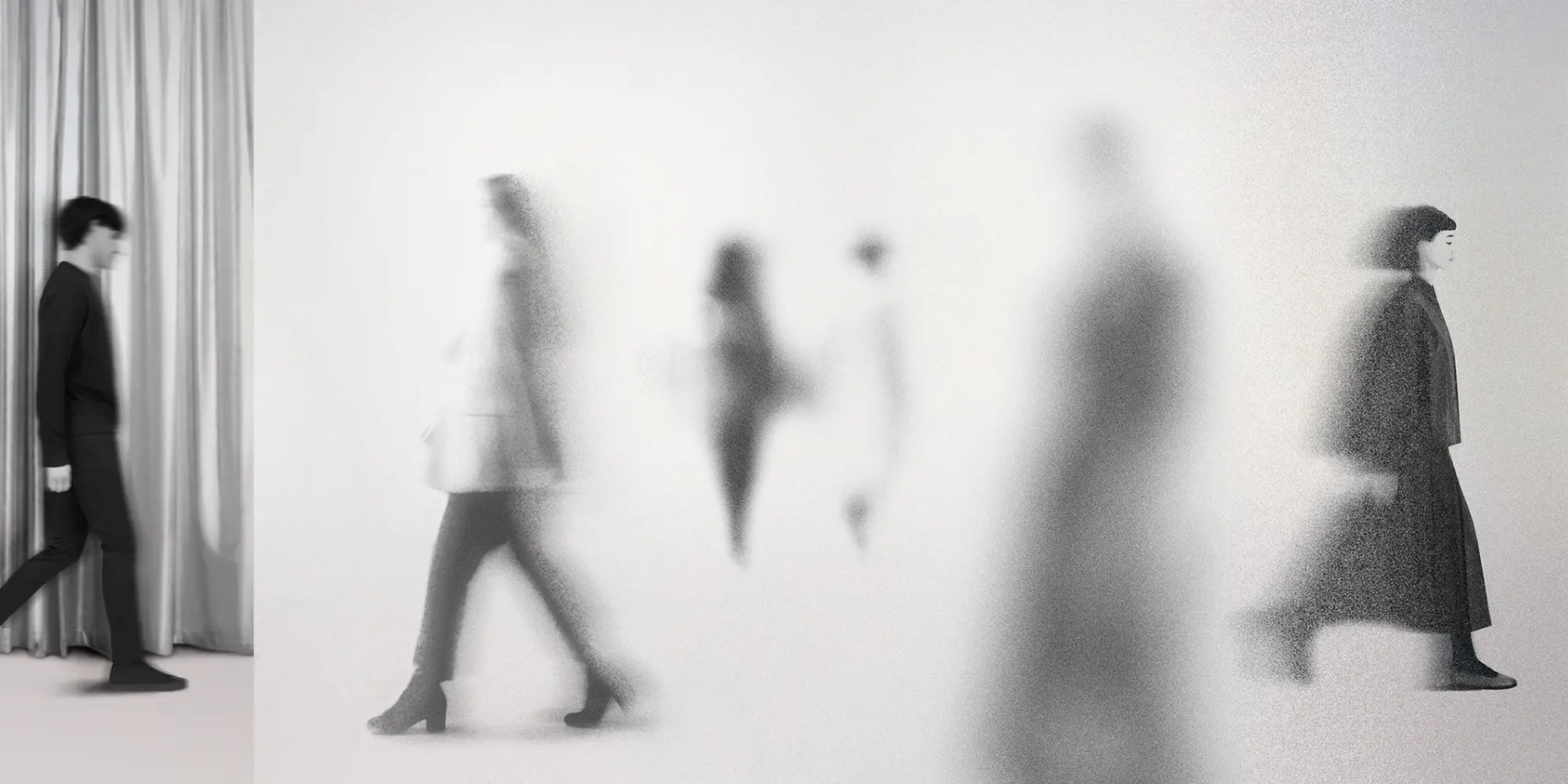 Un banner concettuale con uno sfondo bianco candido e un effetto sgranato e materico. All'estrema sinistra, una persona nitida e a fuoco, vestita con abiti scuri, cammina davanti a una tenda metallica argento lucido. Il resto del banner mostra diverse figure a silhouette spettrali che camminano in varie direzioni, fortemente sfocate e sfuocate, creando un senso di movimento e anonimato.