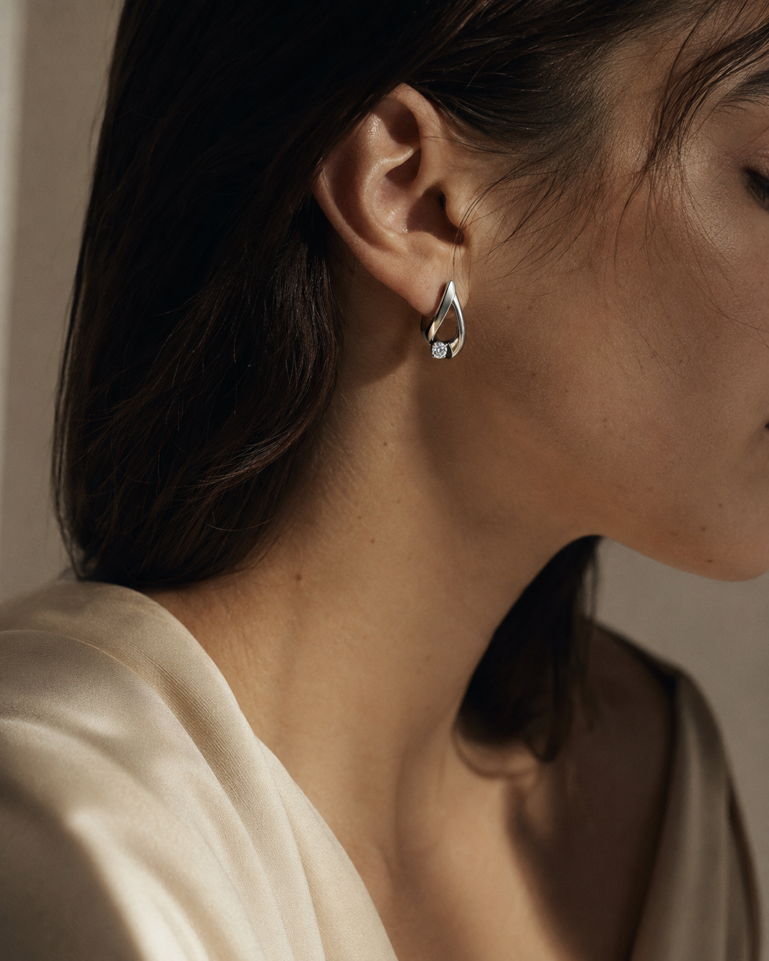 Mujer con arete de diseño contemporáneo y vestimenta satinada