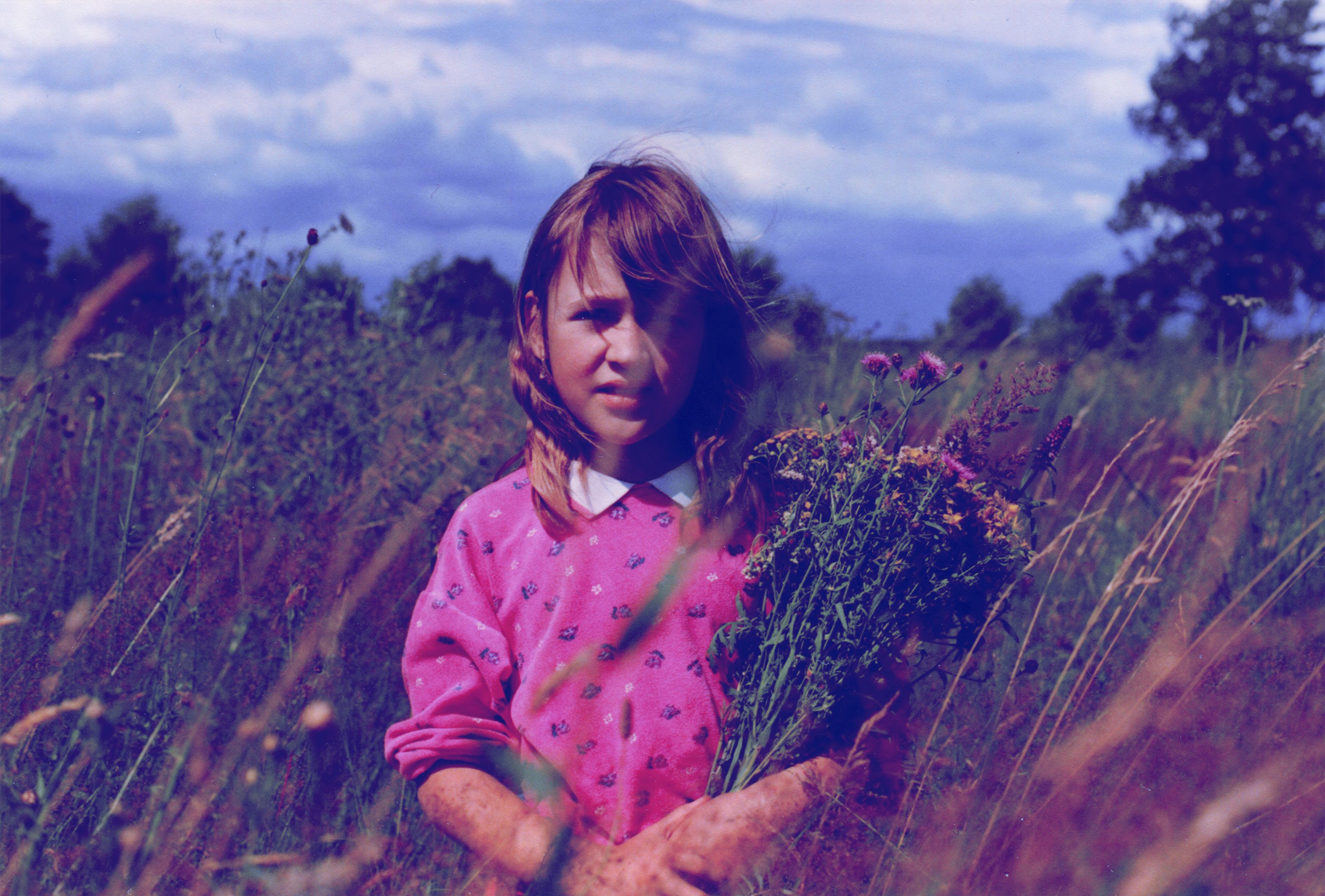 Foto van jong kind in een veld met bloemen