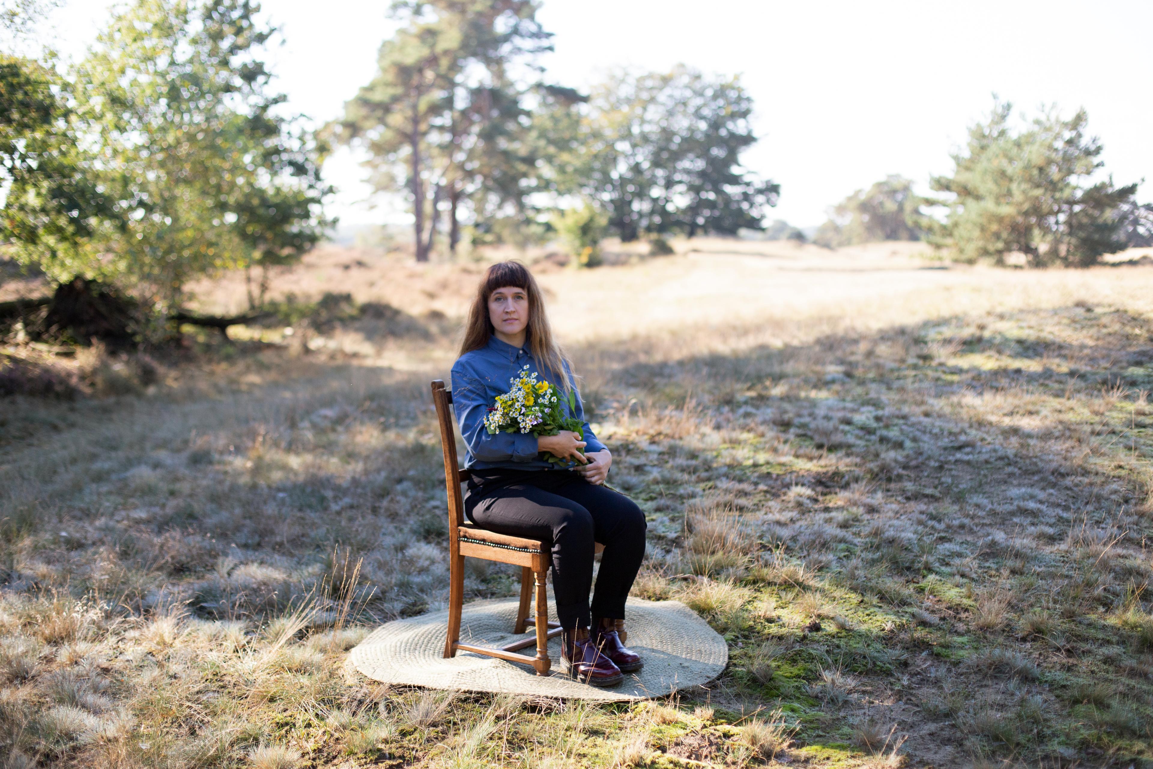 Portretfoto van Miriam Moczko, zittend op een stoel op de heide