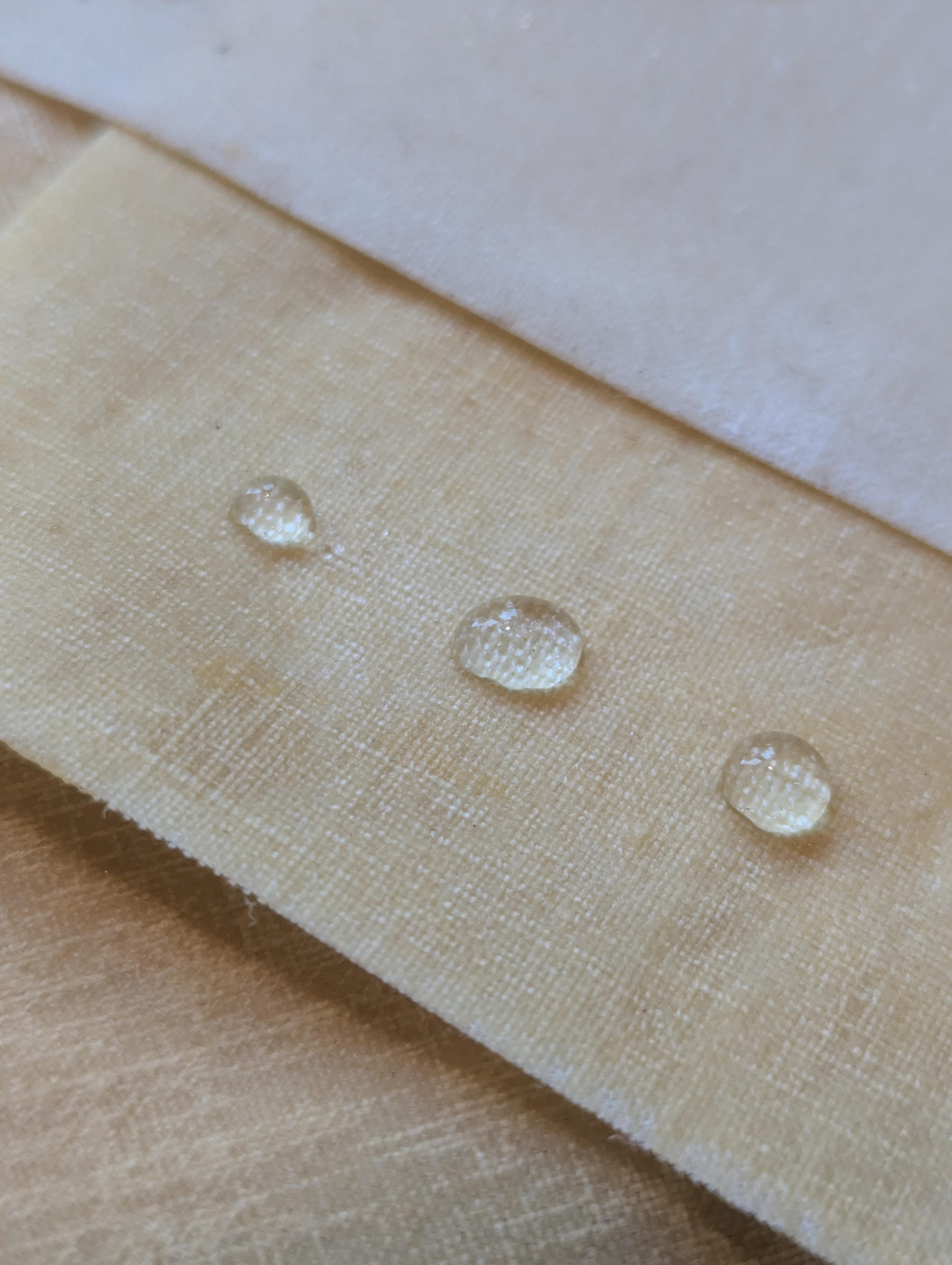 Een sample waarop 3 druppels water liggen die aantonen dat het materiaal waterafstotend is.