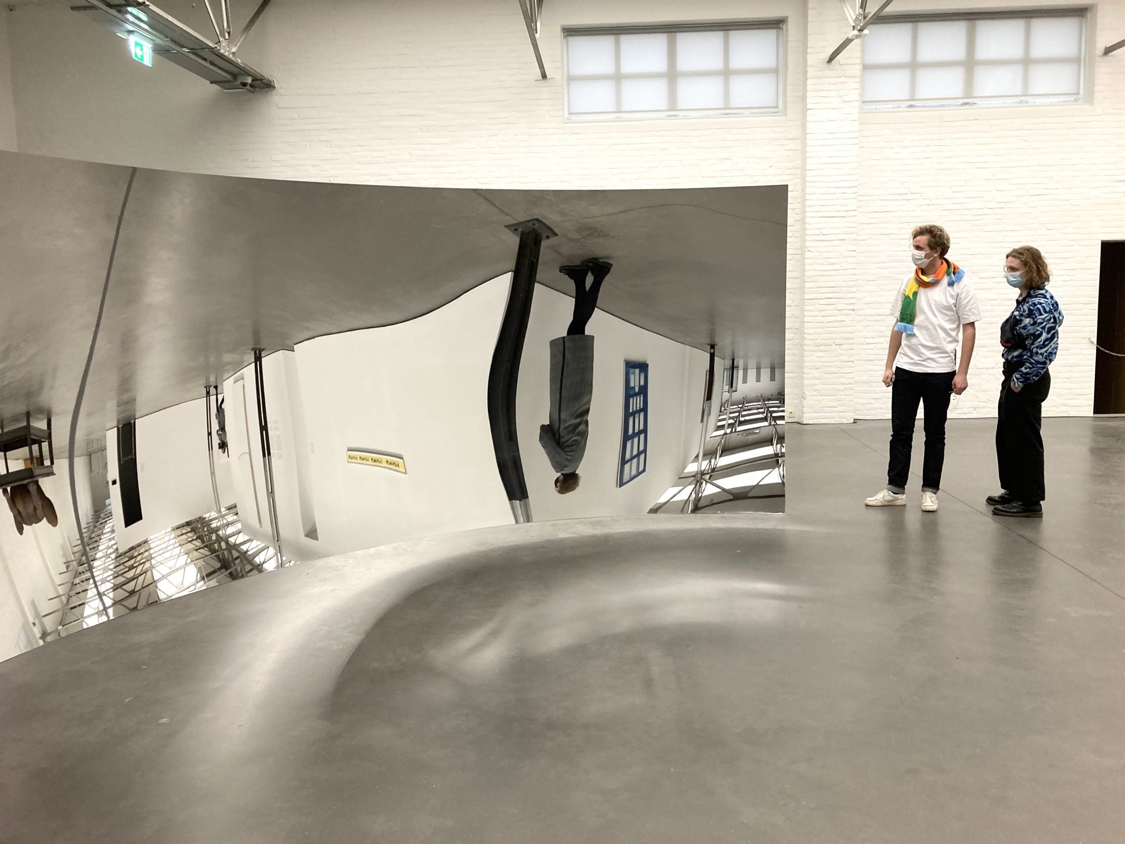 Foto van twee mensen naast een reflecterend kunstwerk