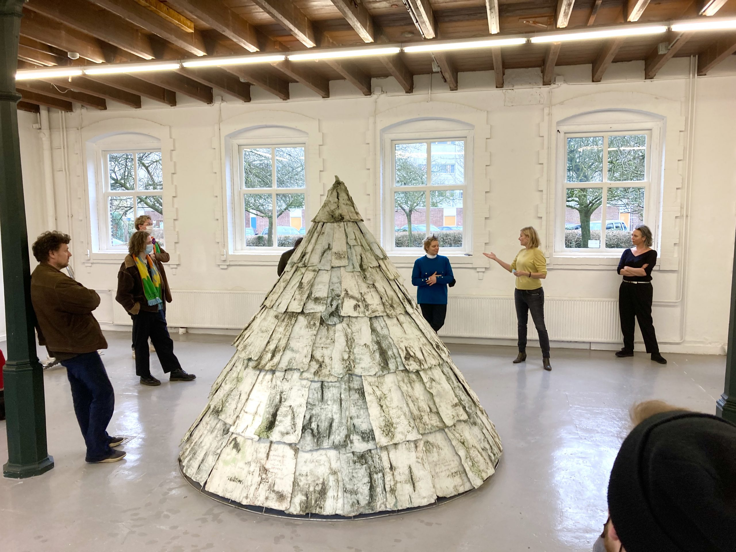 Foto van zes mensen die om een kunstwerk heen staan