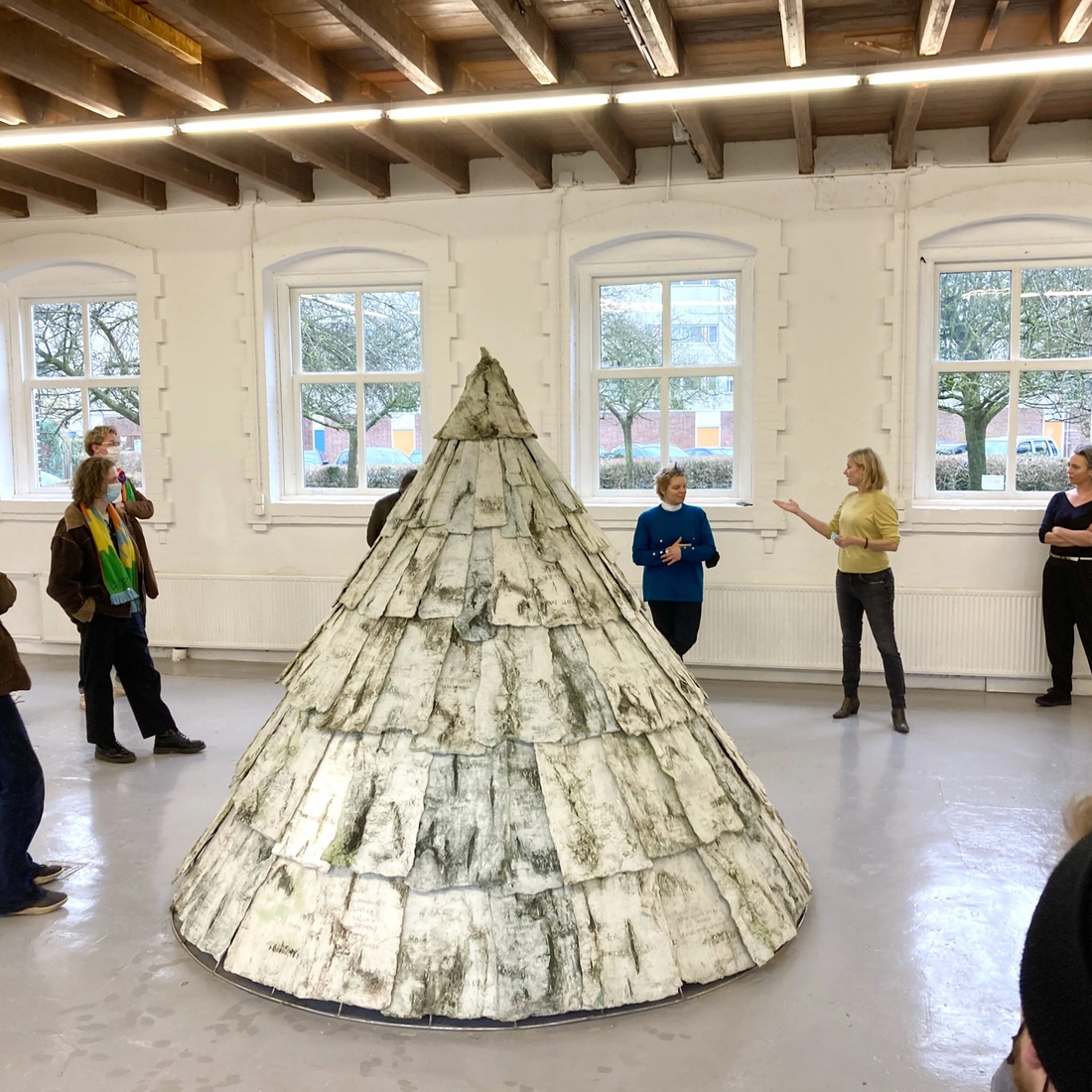 Foto van zes mensen die om een kunstwerk heen staan