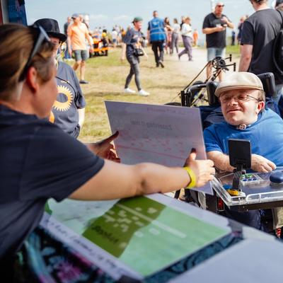 Foto van een menukaart aan de bar die wordt getoond aan een bezoeker in een scootmobiel