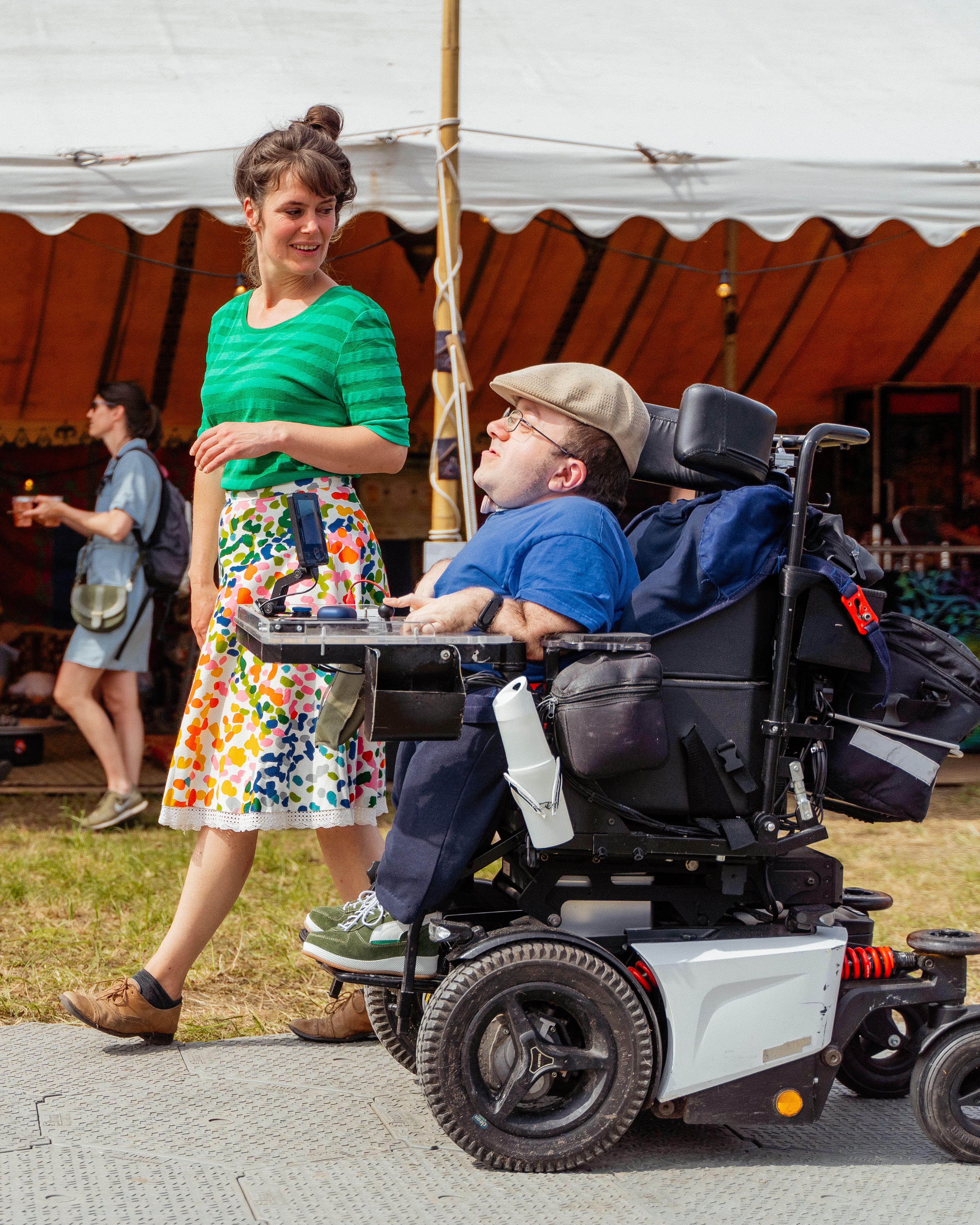 Photo of two people at a festival, one of whom is in a wheelchair
