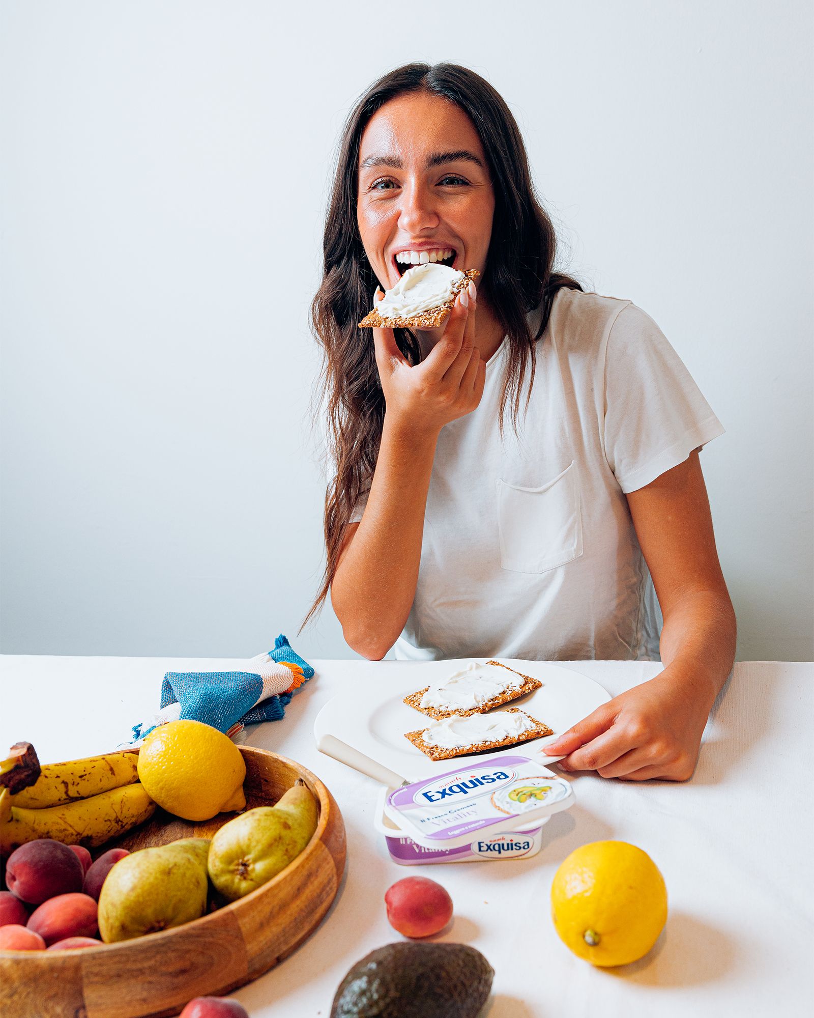 Donna-sorridente-mentre-mangia-una-fetta-di-pane-con-formaggio-fresco