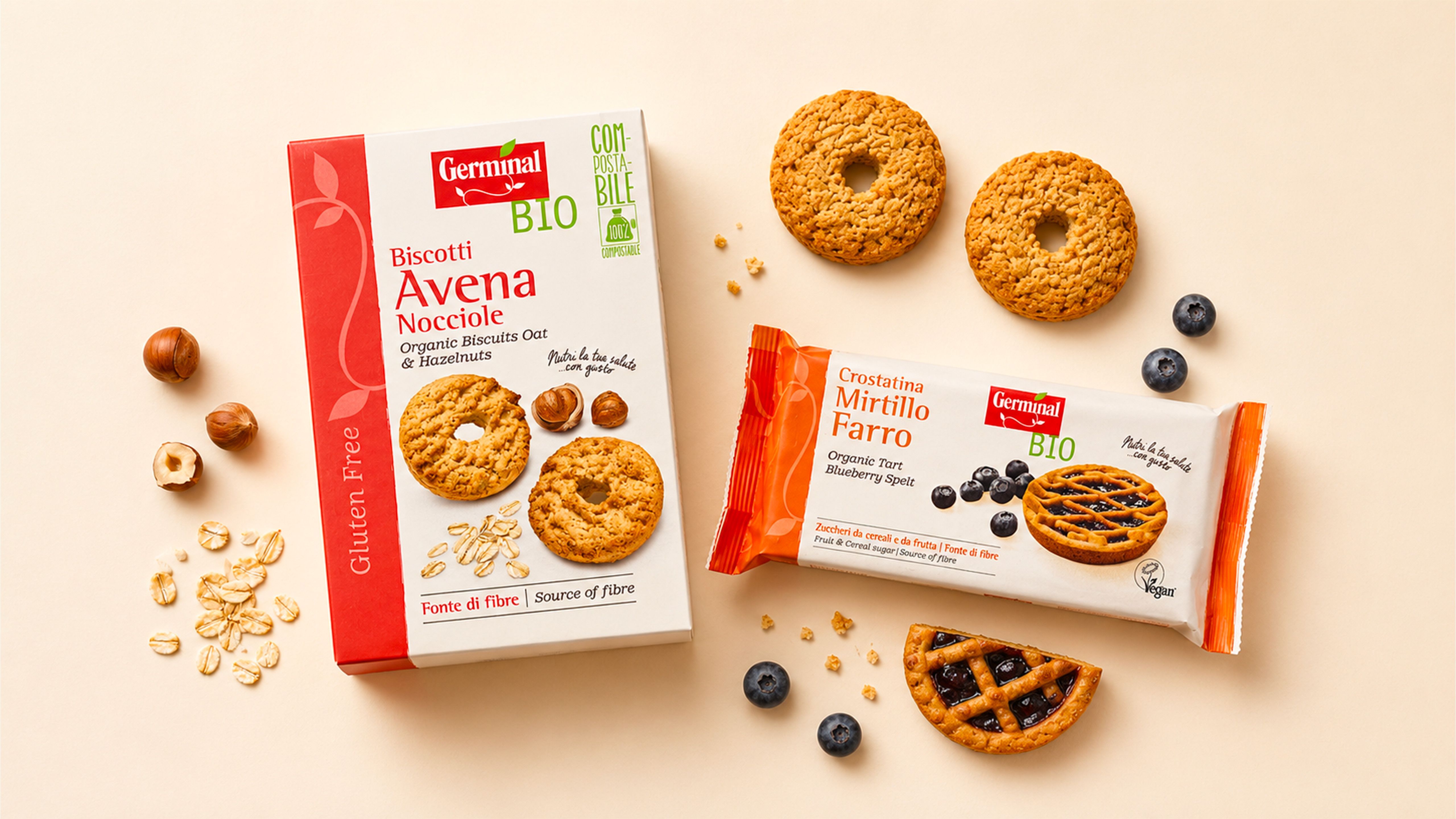 Germinal Bio oat-and-hazelnut biscuit packs and a blueberry-and-spelt tart, with biscuits, hazelnuts, oat flakes, and blueberries on a beige background