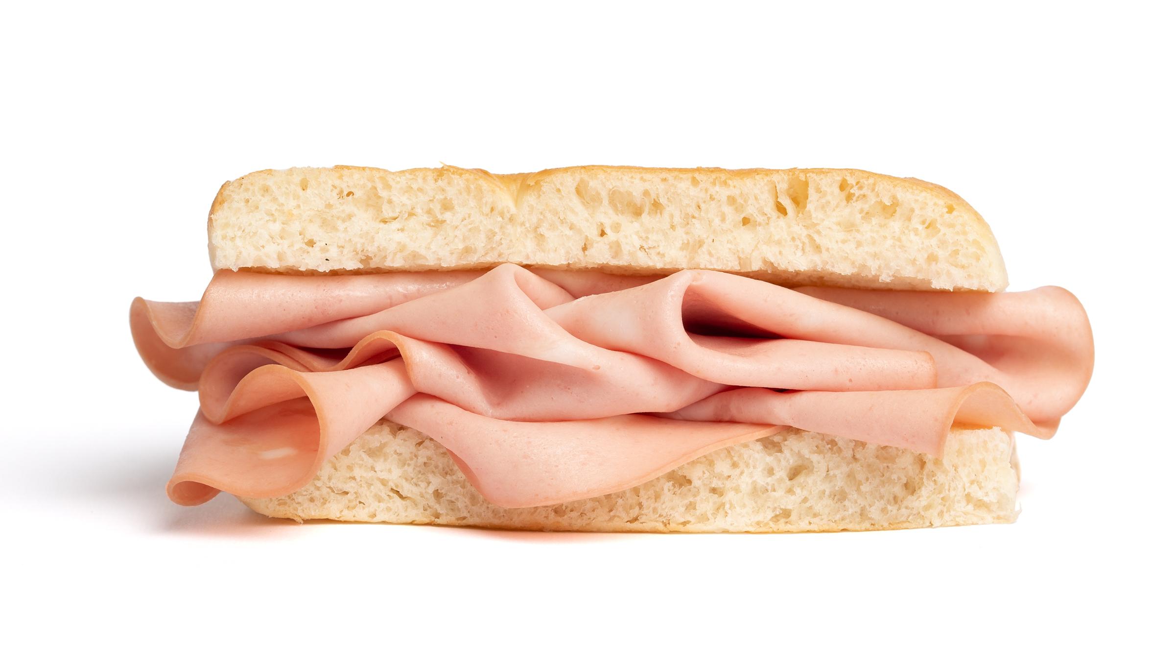 un-inquadratura-frontale-e-ravvicinata-di-un-panino-farcito-con-mortadella-isolato-su-uno-sfondo-completamente-bianco-il-panino-è-tagliato-a-metà-in-senso-orizzontale-mostrando-la-mollica-soffice-della-focaccia-o-del-pane-mentre-le-fette-di-mortadella-rosa-sono-disposte-in-modo-ricco-e-ondulato-all-interno