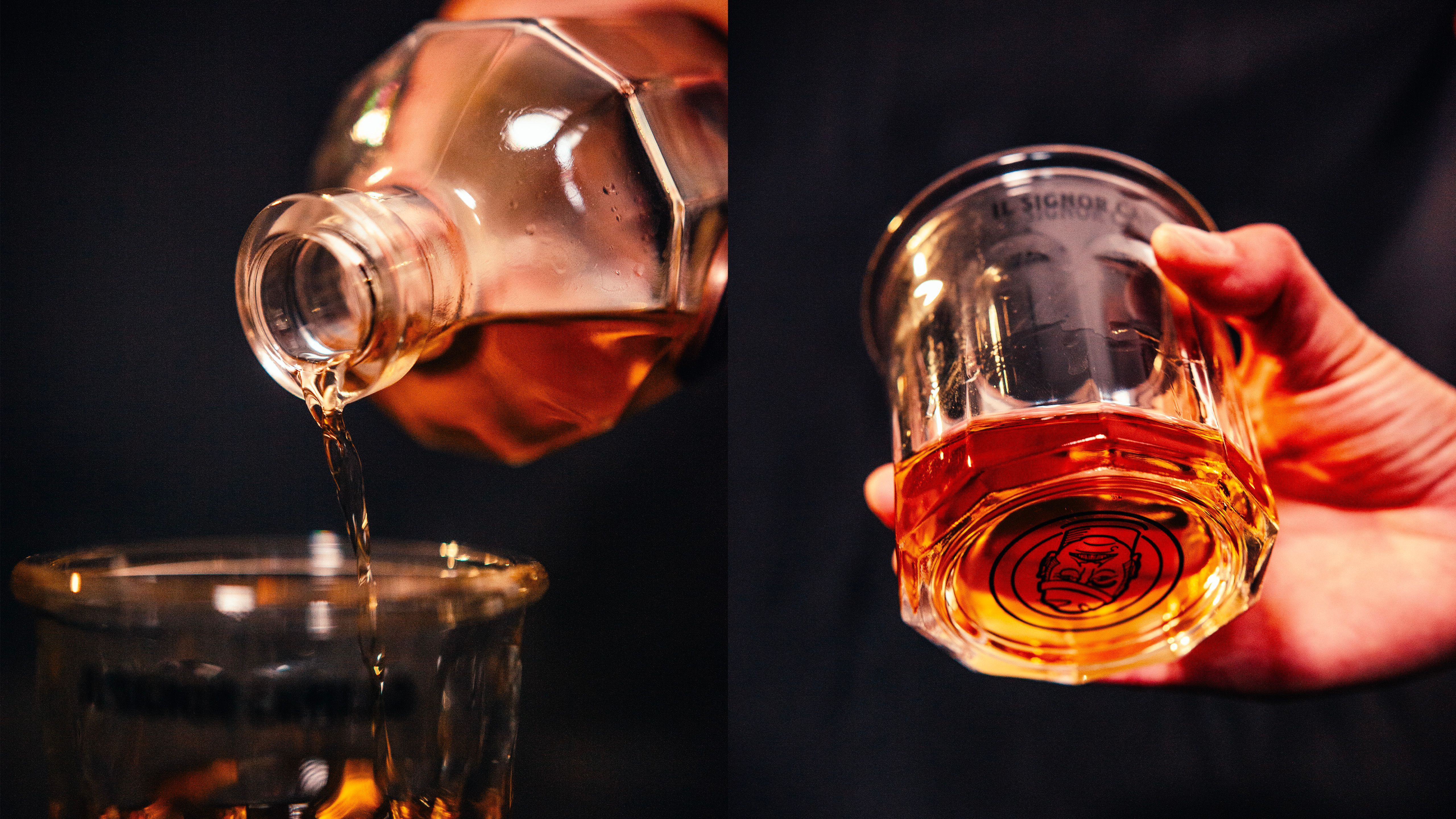 Amber spirit poured into an Il Signor Camillo glass, held in hand against a dark background