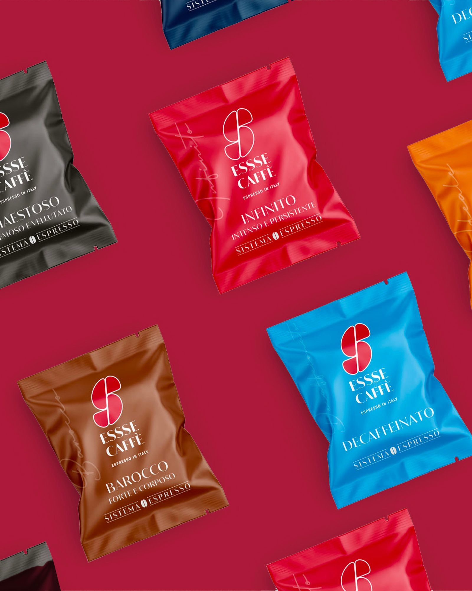 Essse Caffè single-serve pods — Infinito, Barocco, Decaffeinato and Maestoso — arranged on a red background.