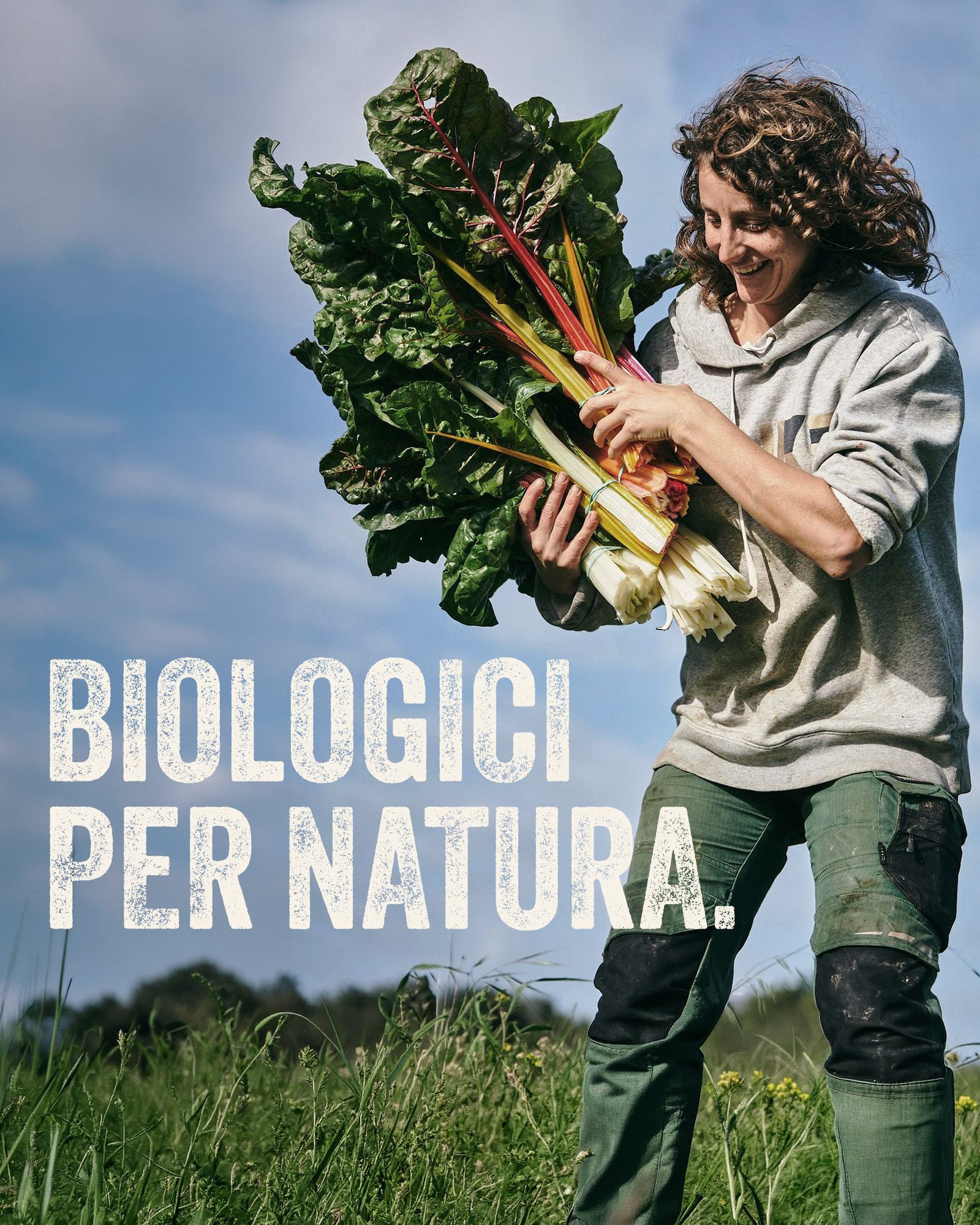 Woman in a field holding a large bunch of chard, with the tagline 'organic by nature'