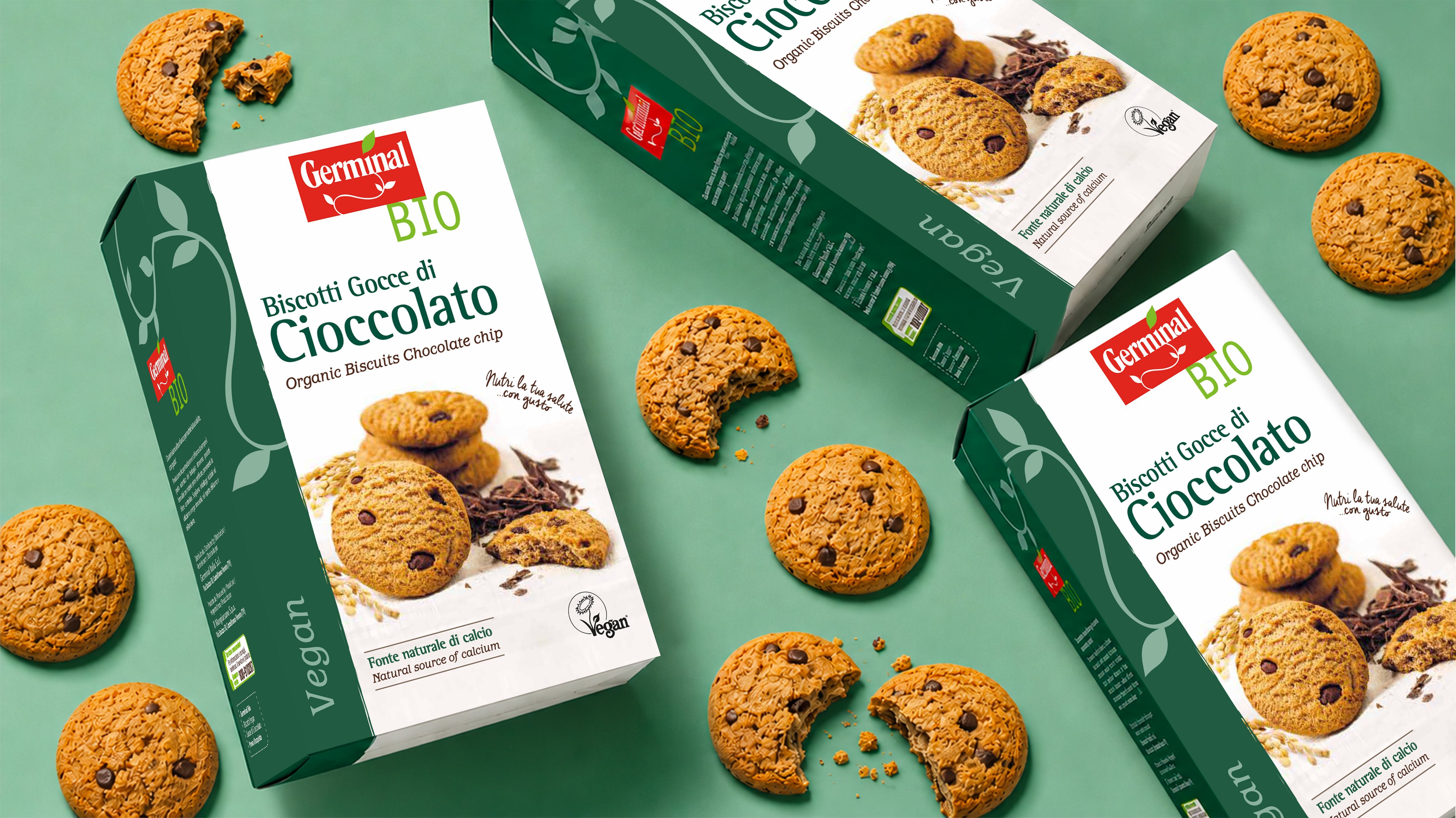 Germinal Bio vegan chocolate chip biscuit packs surrounded by whole and broken biscuits on a green background
