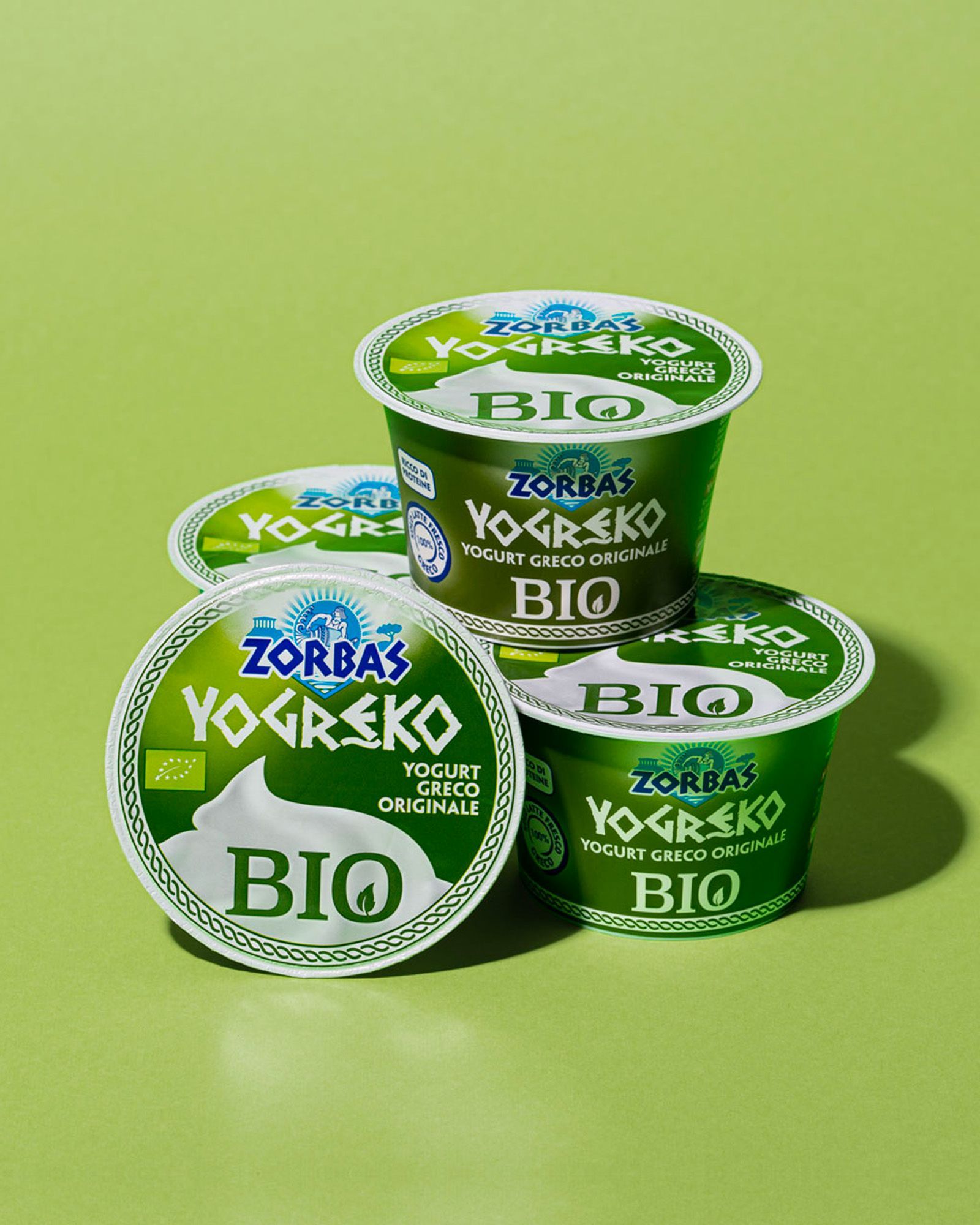 A composition of Zorbas promotional graphics featuring yogurt, feta, hummus, Greek sauces, products and people, on a light-blue background.