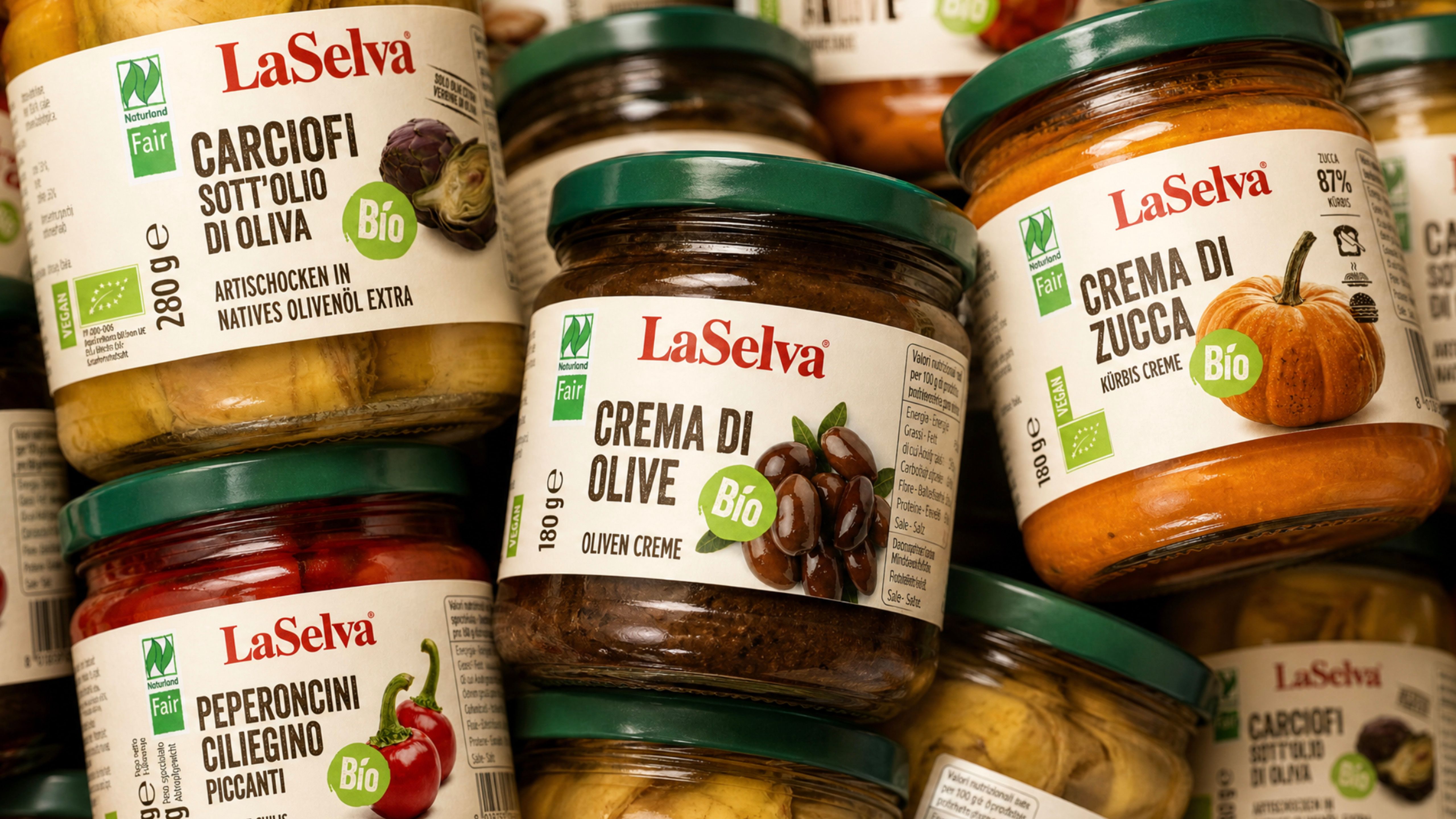 Jars of La Selva organic products — olive cream, pumpkin cream, artichokes in oil, and spicy chili peppers — on a shelf