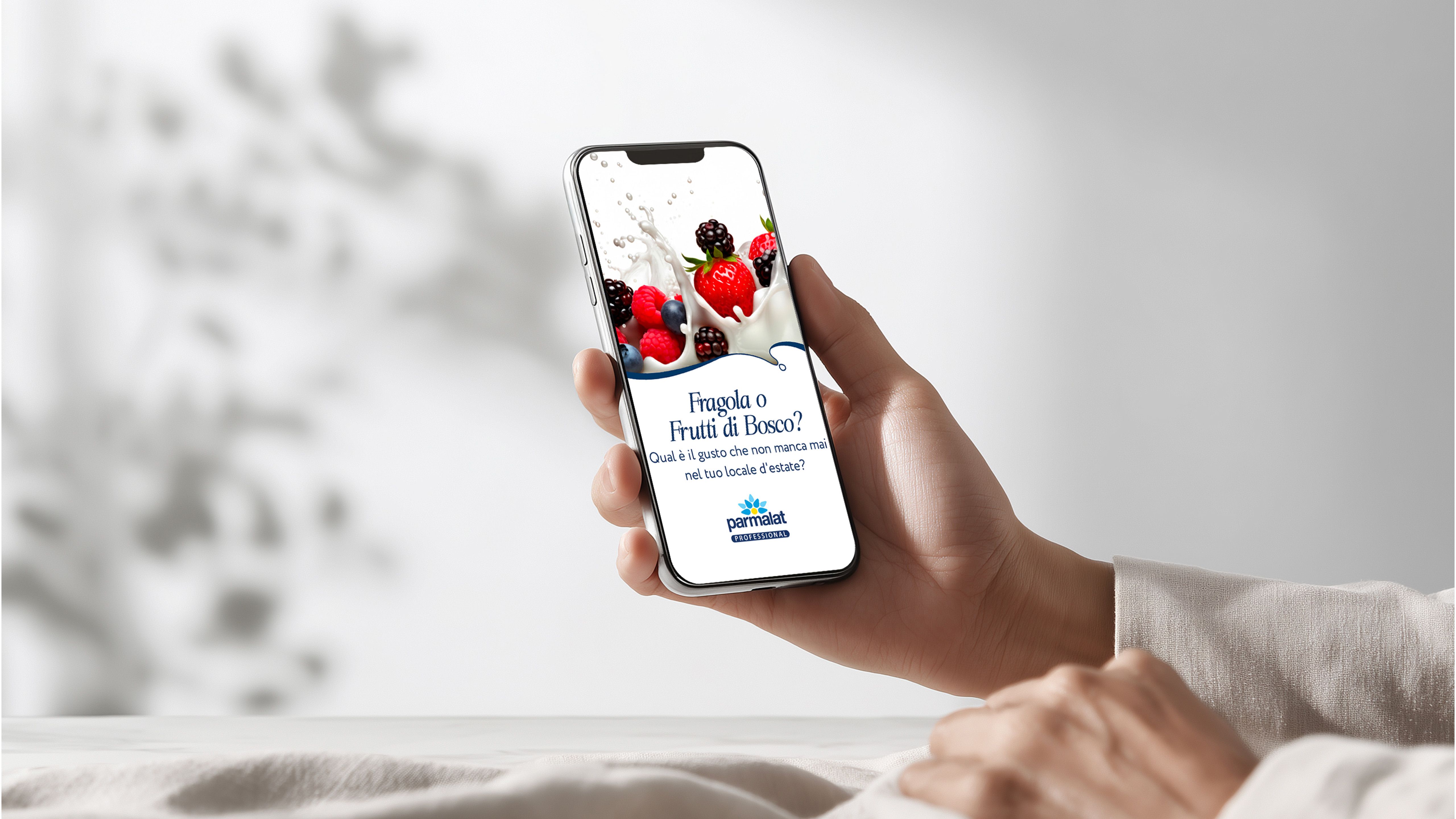 Hand holding a smartphone showing Parmalat Professional content on strawberries and mixed berries, on a white background