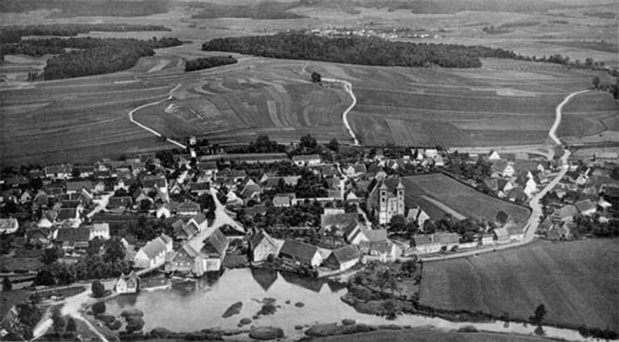 Historisches Luftbild von Auhausen: das Dorf mit der Klosterkirche zwischen Weiher und Feldern, dahinter der Kellerberg.