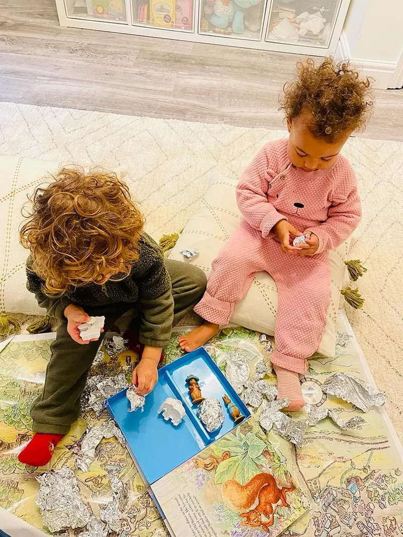 two-children-play-with-foil-and-toys-on-a-colorful-rug