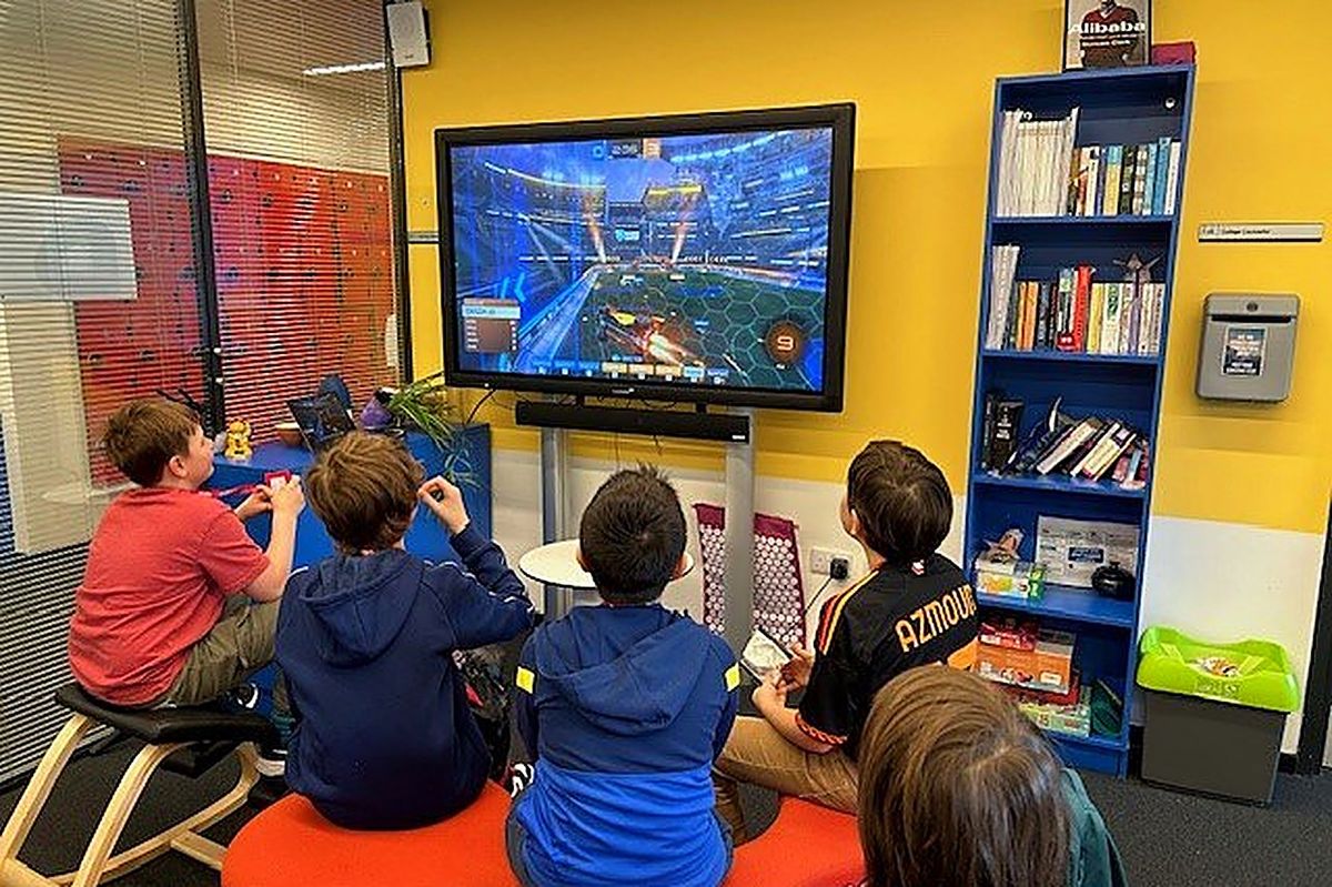 Pupils on beanbags watching a Rocket League match on a large screen