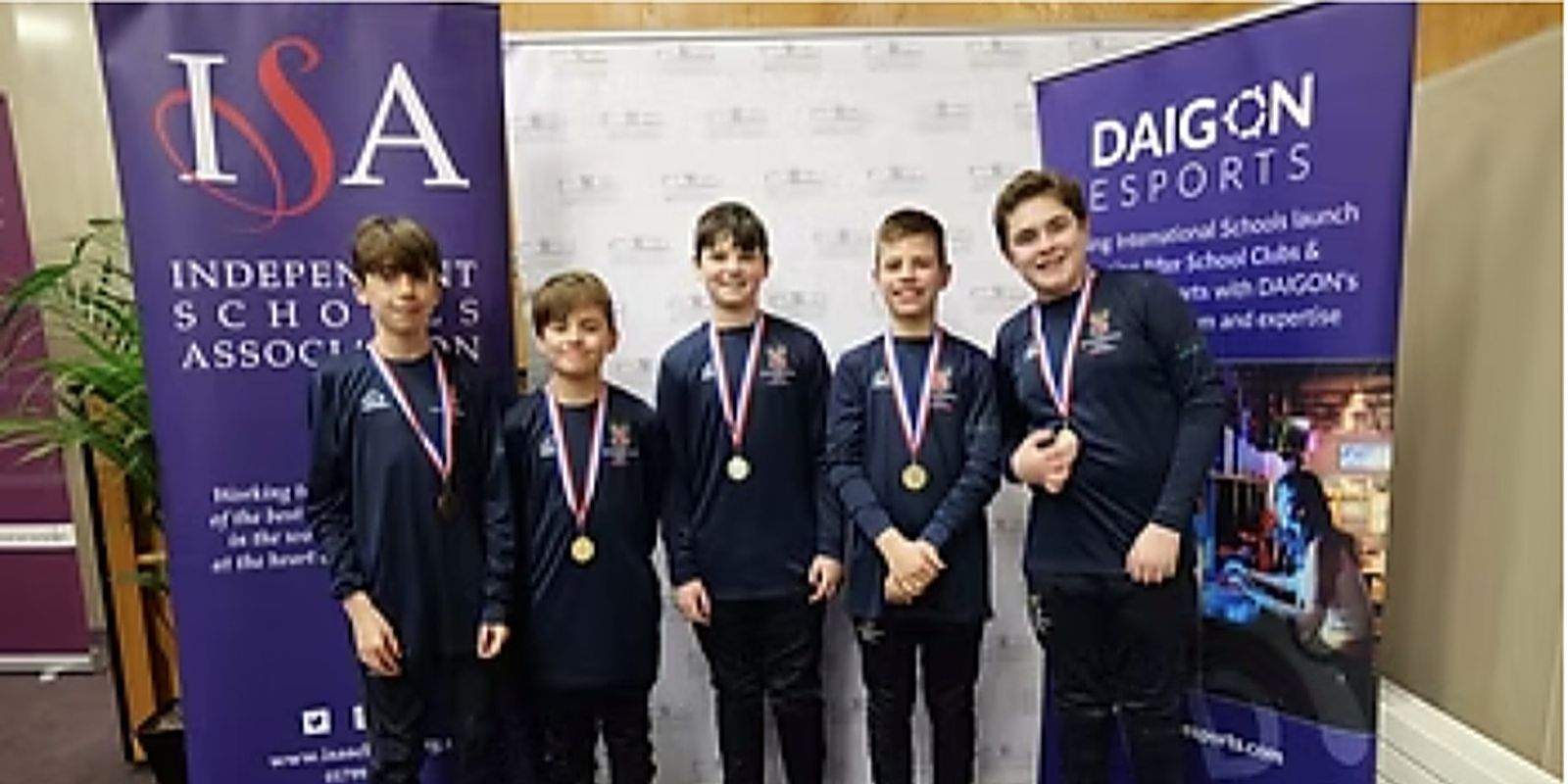 Five medal-winning pupils in front of ISA and DAIGON banners at the National Finals