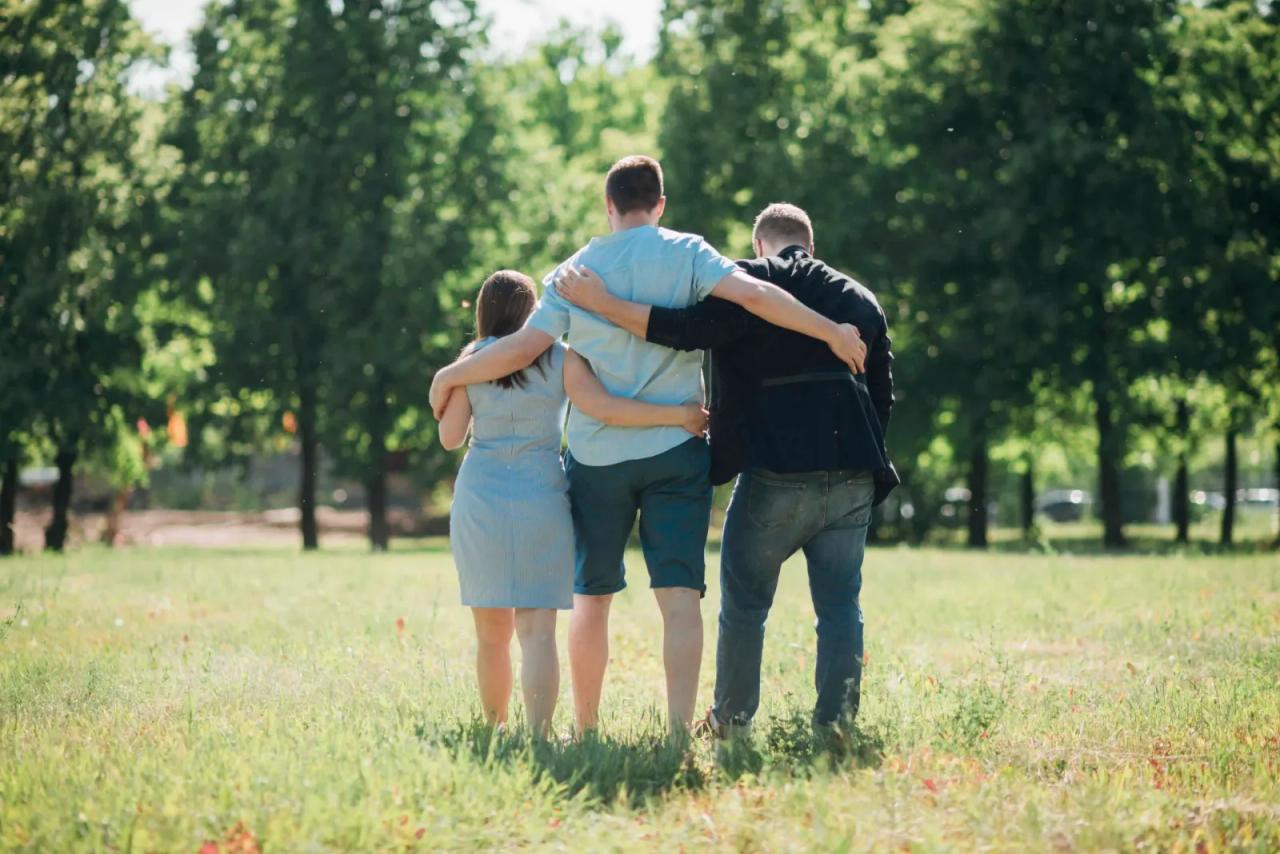 3 people in an enm relationship walking through a field