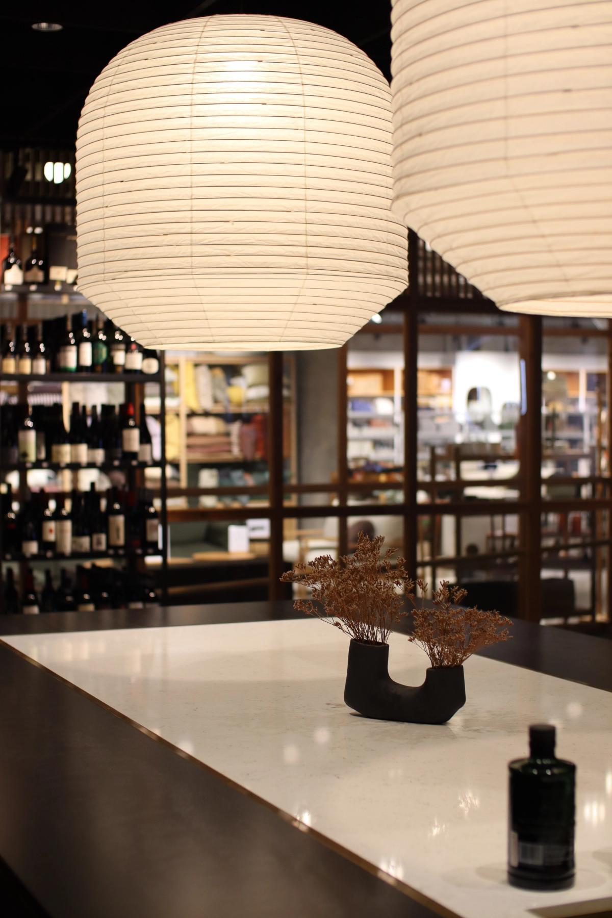 view across island bar showing pandants alcohol on display on shelving in the background
