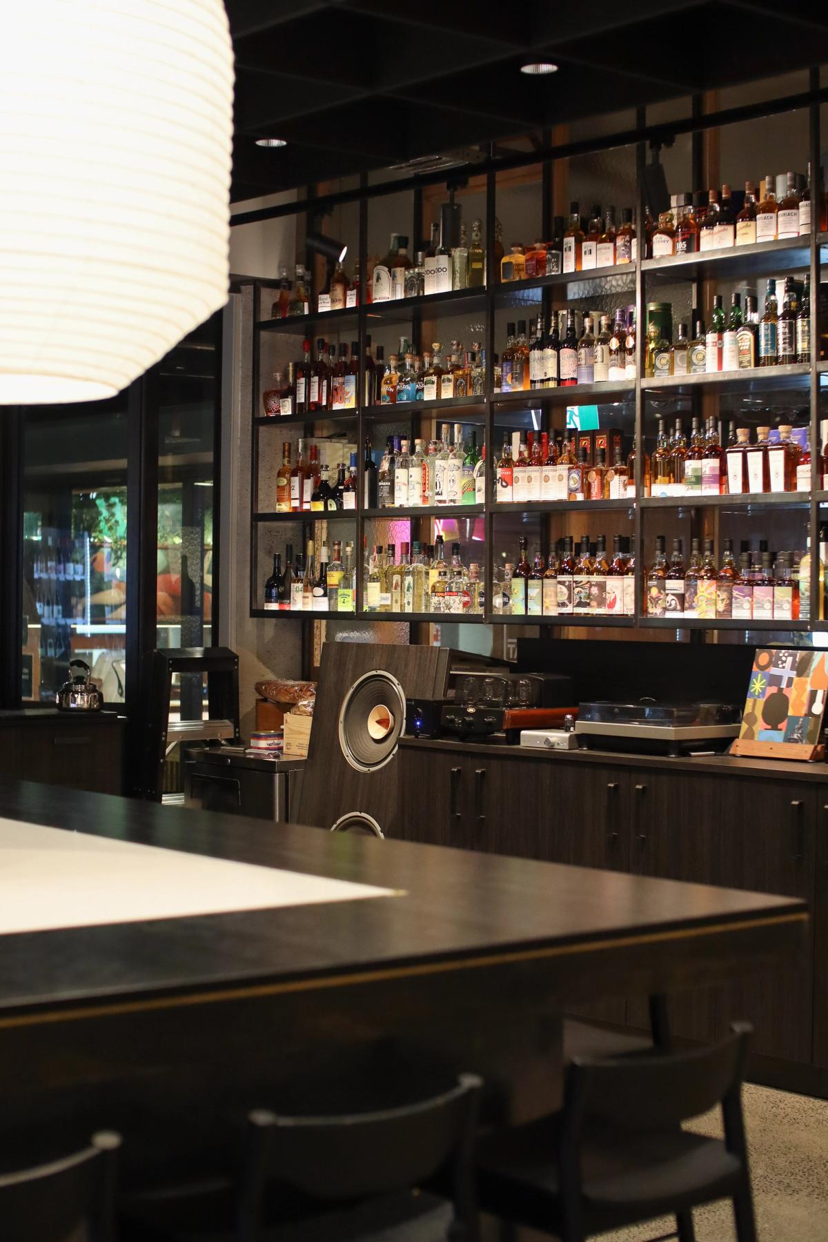 bottles of alcohol arranged on steel shelving with record player and amp on display cabinet