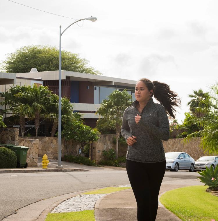 Woman jogging through a neighborhood with homes in the background