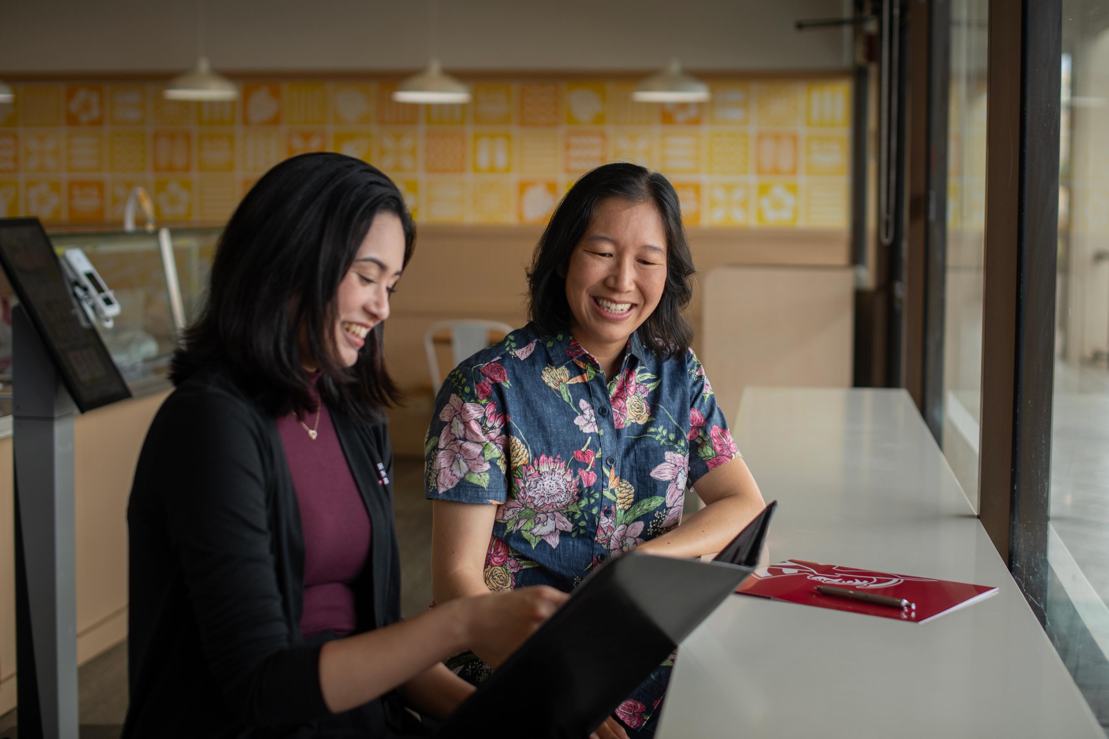 L&L Hawaiian Barbecue Entrepreneur Elisia Flores looks at a document with her Hawaii National Bank Relationship Officer Kacie Bergantinos
