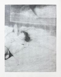 A person with dark hair is lying on their side on a bed or soft surface, partially covered by a light-colored blanket or sheet.
