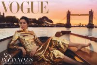 A person wearing a shiny gold dress is reclining on a boat at sunset with a city skyline and a bridge in the background, featured on a Vogue magazine cover.