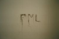 Hair strands arranged on a tiled wall to form the letters F, M, and L.