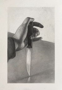 A hand is holding a knife with the blade pointing downward, resting on a flat surface.