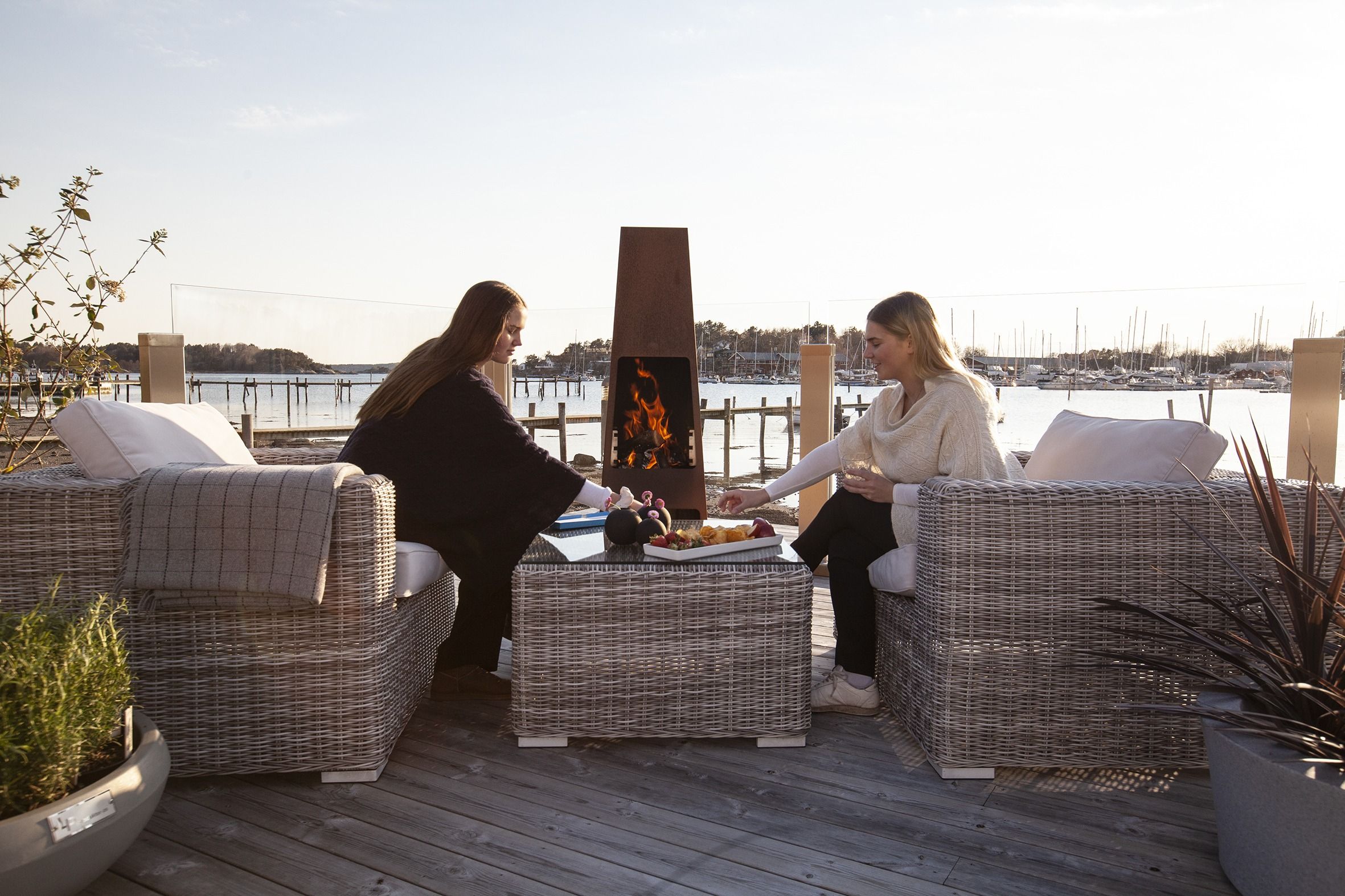 Jøtul utepeis på brygge ved sjøe med to jenter som hygger seg