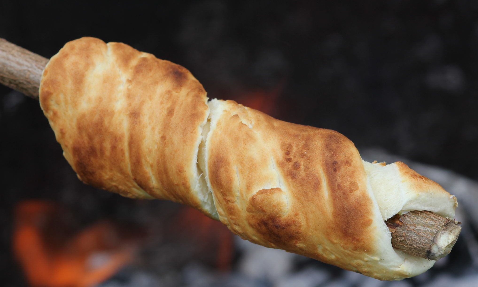 Brød stekt på pine over flammer i utepeis