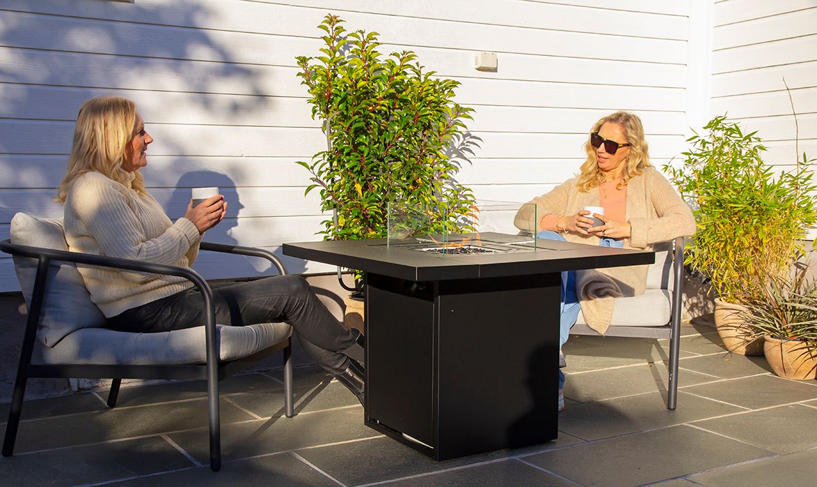 Bord med innebygd biopeis på terrasse med to personer sittende rundt