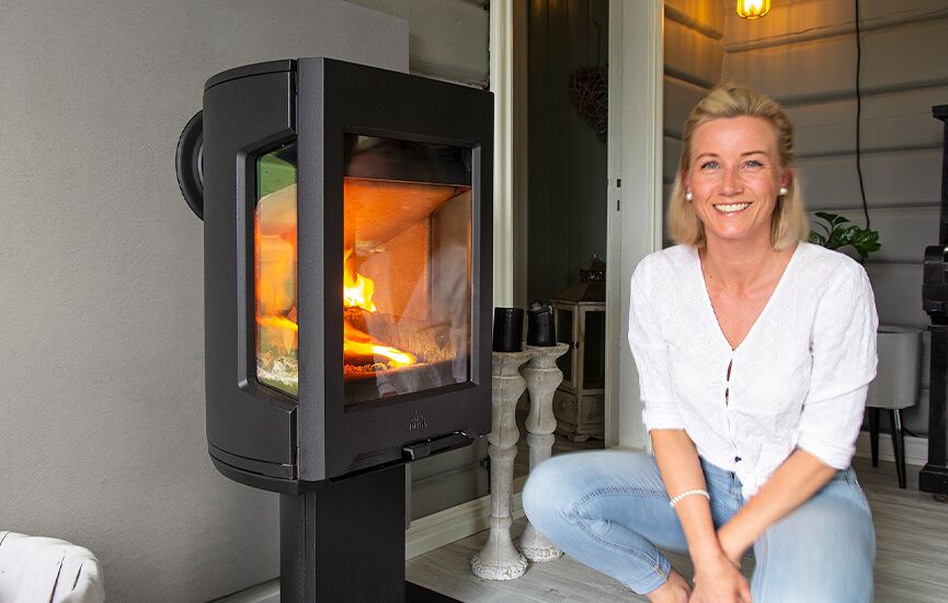 Person sittende ved siden av Jøtul F 167 vedovn med flammer