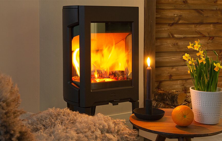 Rentbrennende vedovn i hytte med levende flammer og varm belysning