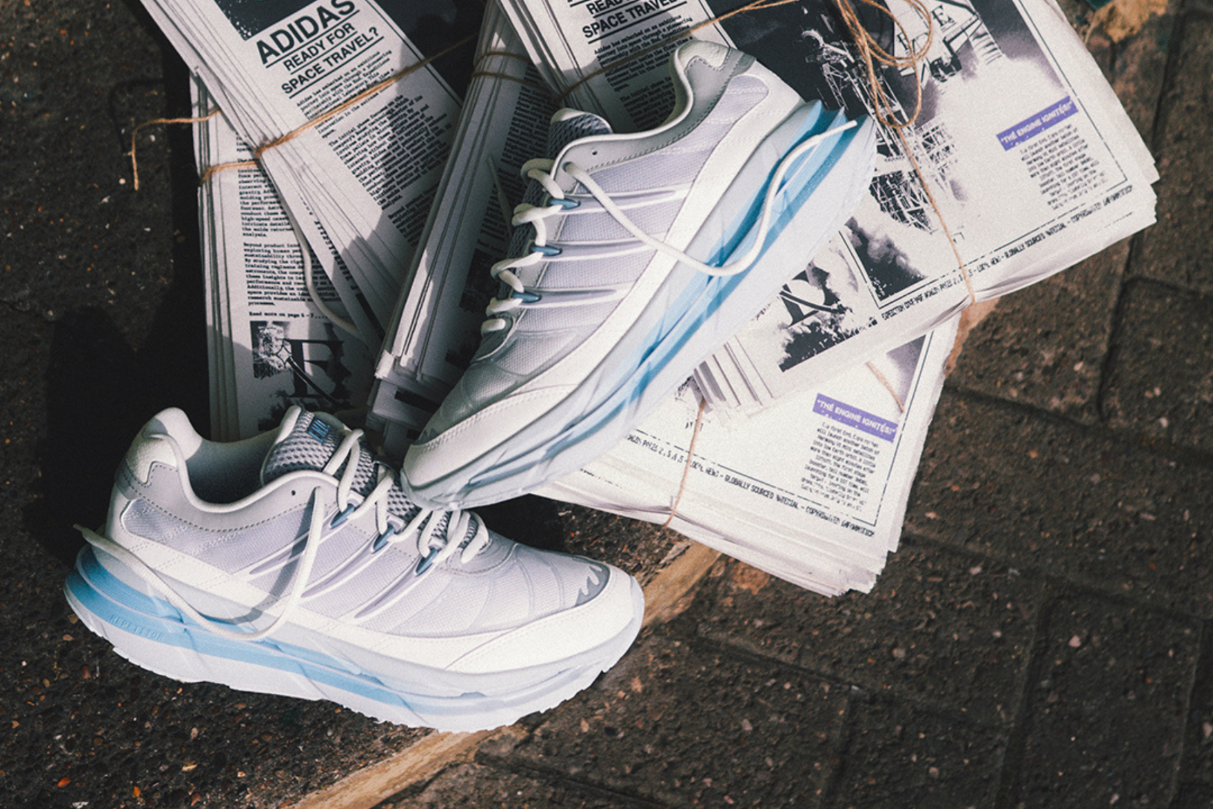 adidas sneakers stacked on top of some newspapers