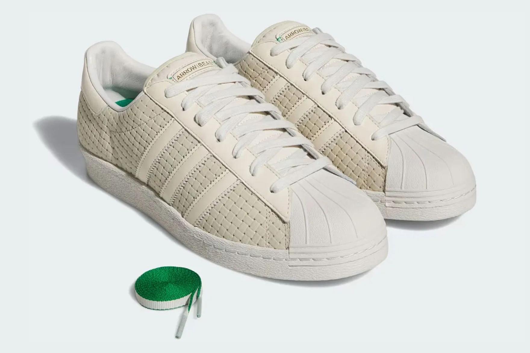 White adidas sneakers sitting on pale blue surface