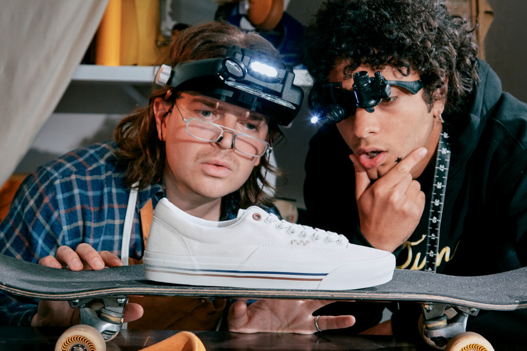 two people looking in awe at a vans sneaker on a skateboard