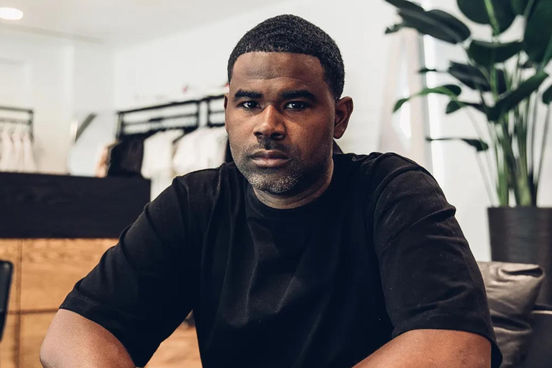Black man in black t-shirt sitting inside a retail space
