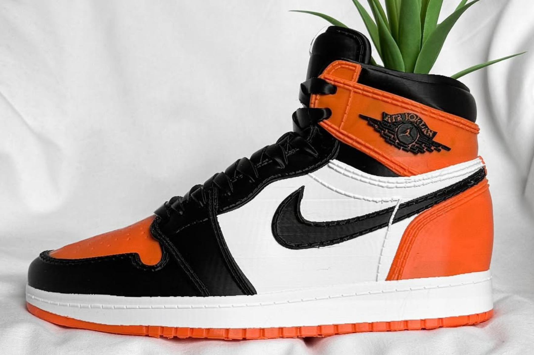 A 3D-printed AJ1 sneaker in 'shattered backboard' with a plant inside