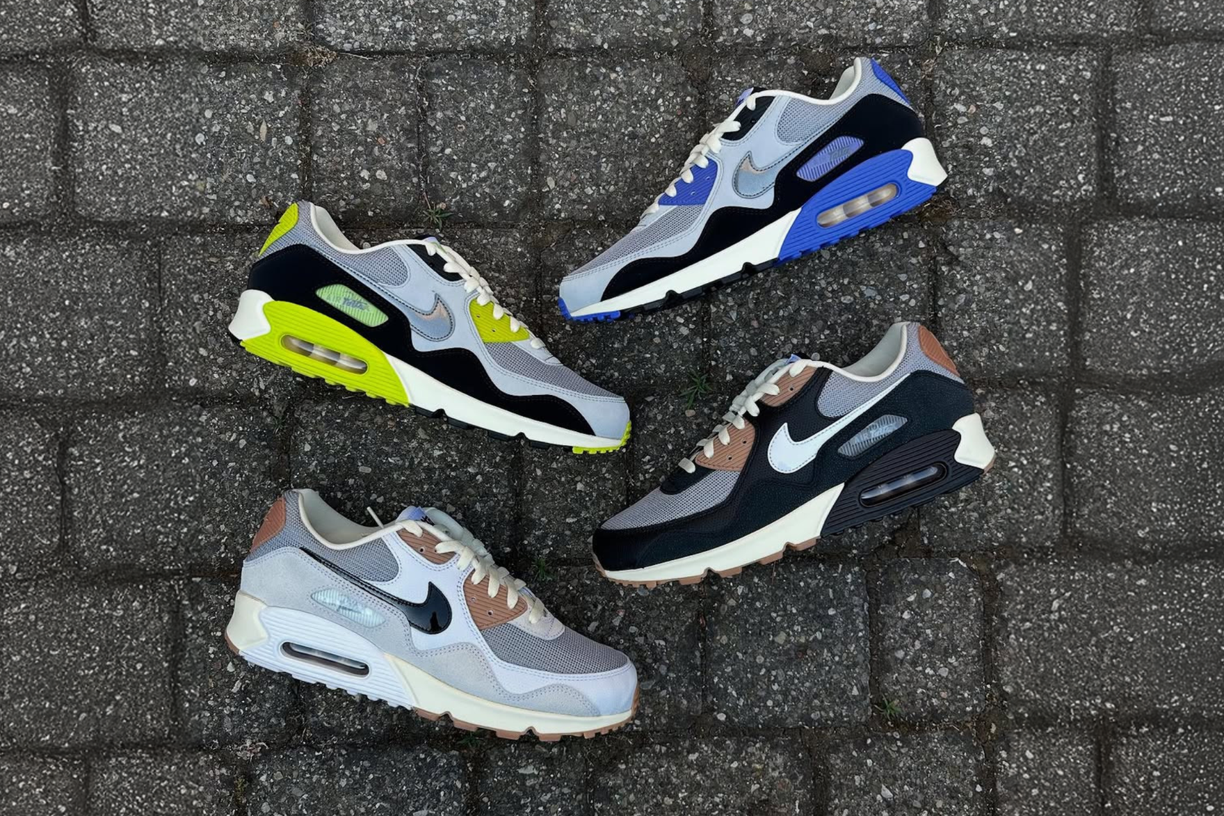 All four Patta x Nike Air Max 90 sneakers on black paved surface