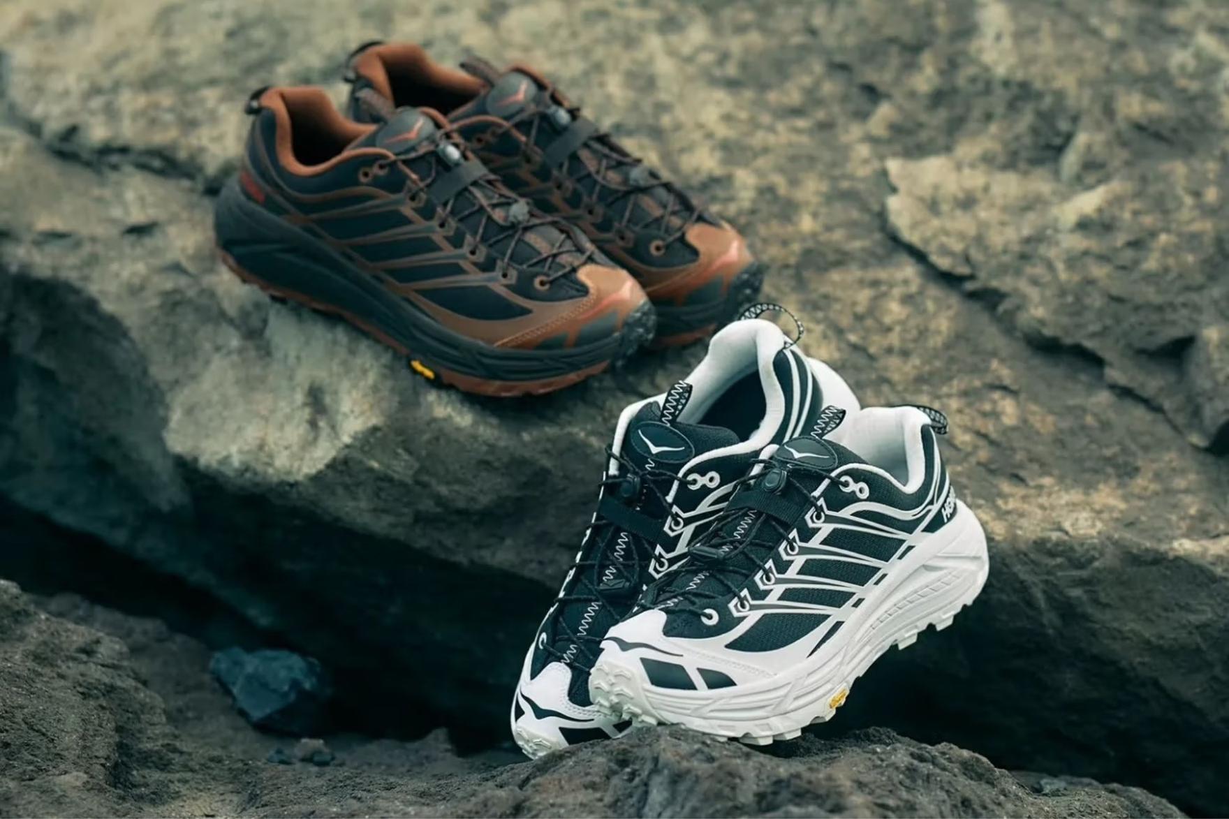 Brown and white pairs of HOKA sneakers sitting on beach rock