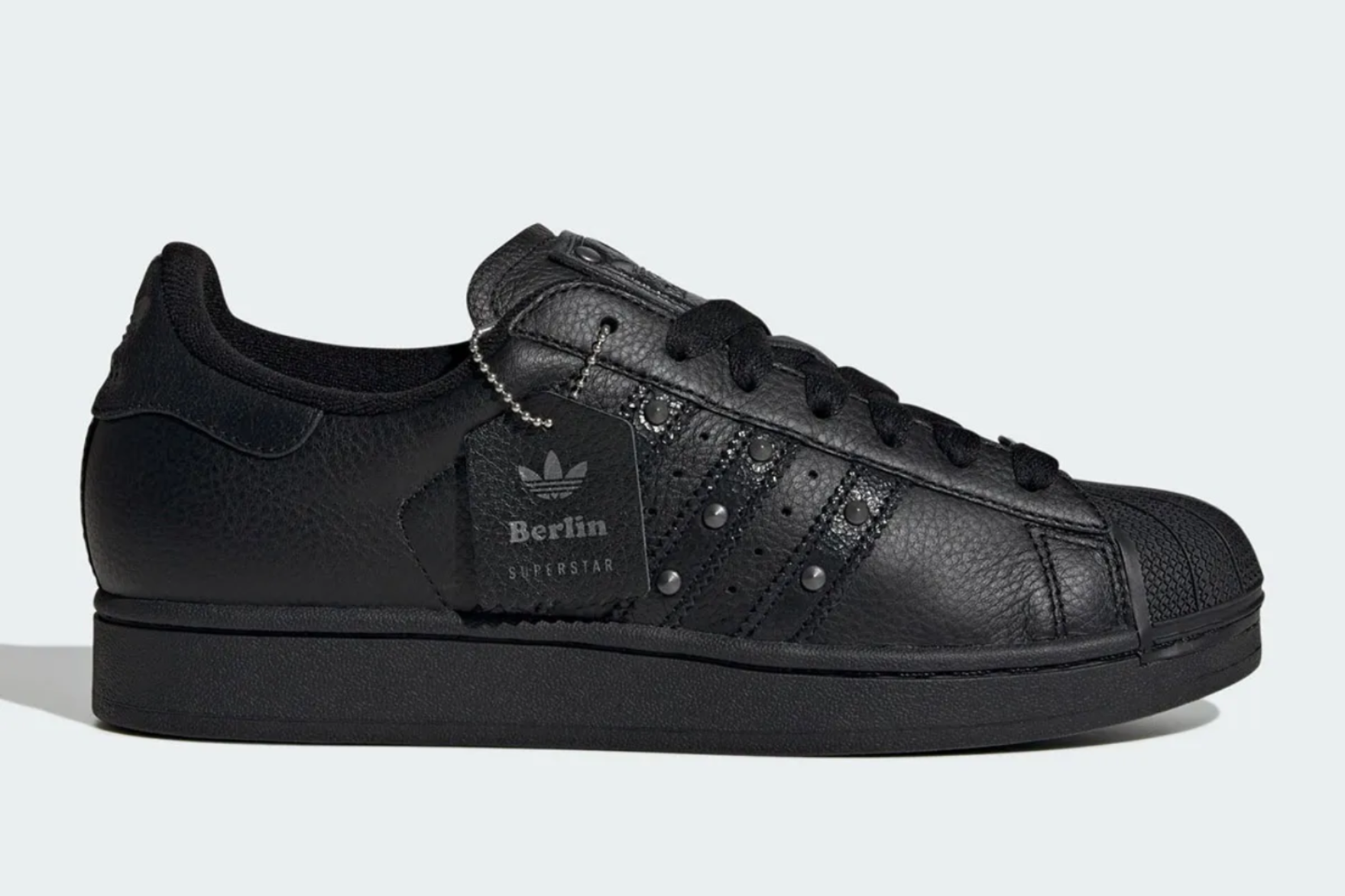 black studded adidas superstar on blue background